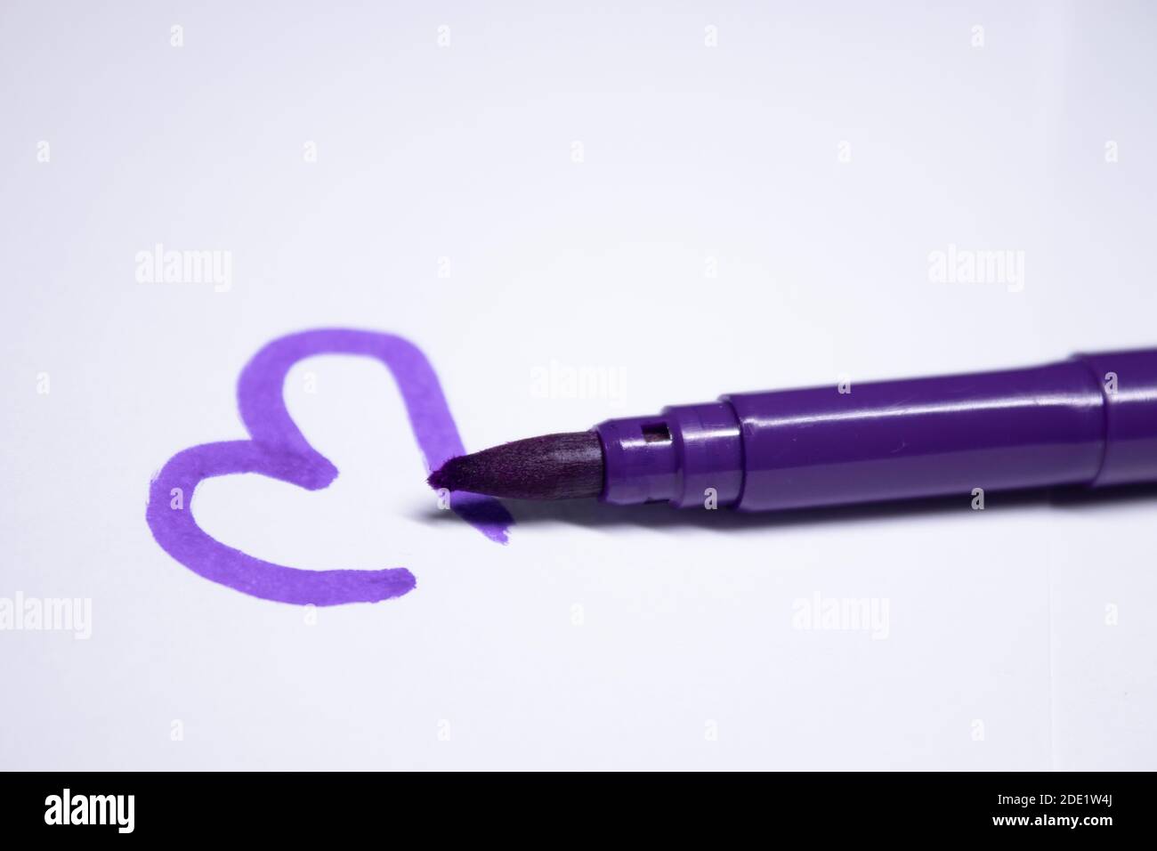 pennarello viola con cuore dipinto accanto. concetto di cancelleria. spazio di copia. isolato. Foto di alta qualità Foto Stock