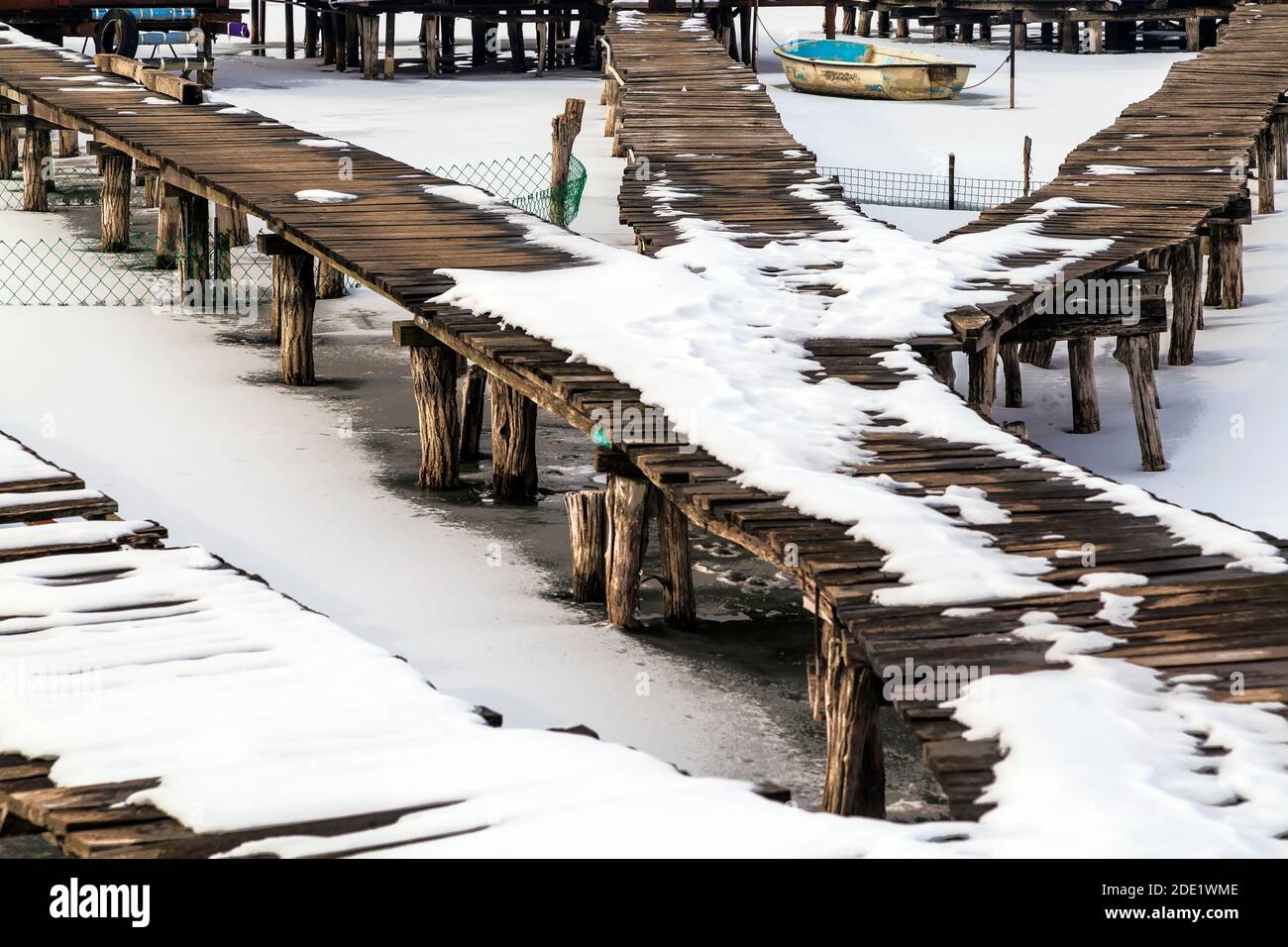 Pier in legno con impronte nella neve sul lago ghiacciato. Foto Stock