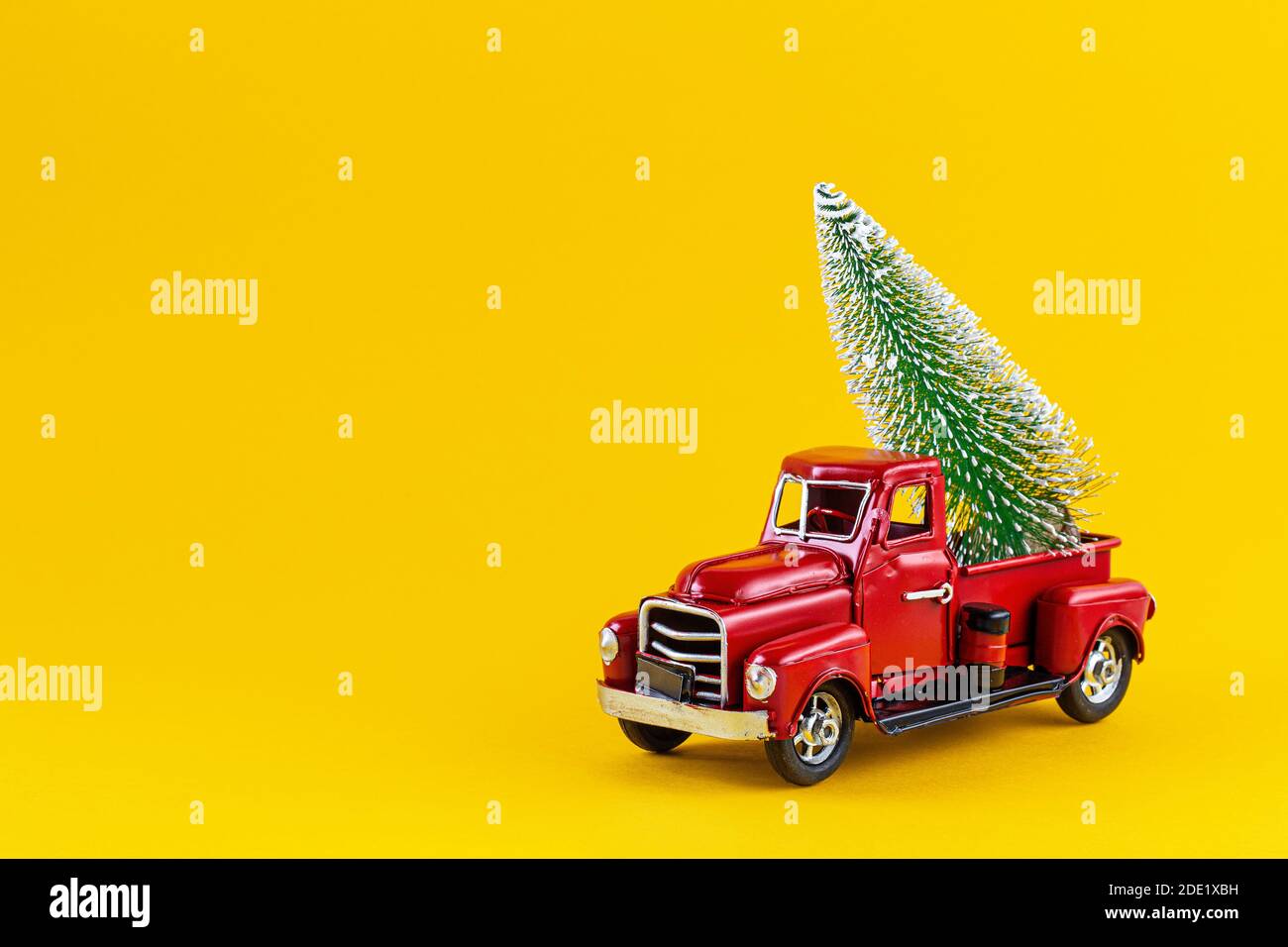 Camion giocattolo rosso retrò con albero di Natale sul corpo del camion su sfondo giallo. Consegna, natale, Capodanno. Modello giocattolo vintage con Christma Foto Stock