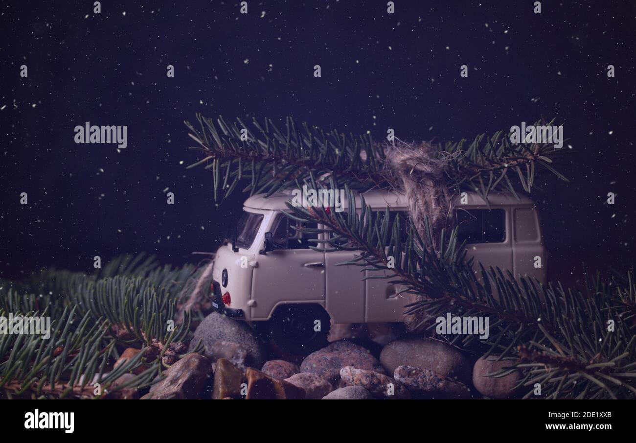 Concetto di Natale. Una piccola macchina giocattolo porta un ramo di un albero di Natale Foto Stock