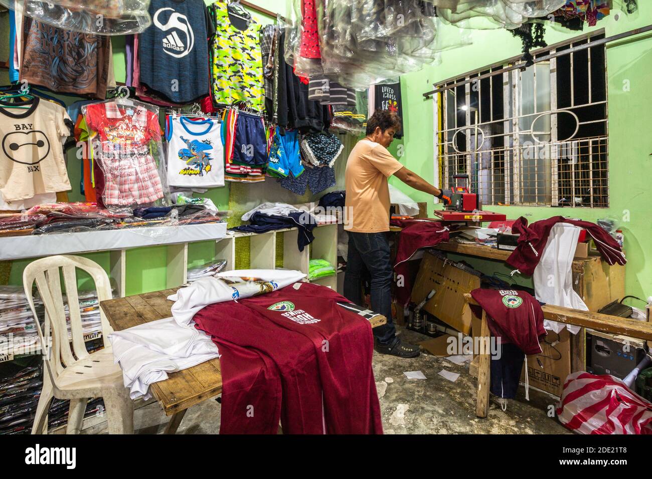 Un proprietario di una tshirt tipografica che lavora su una camicia con la sua macchina da stampa a Batangas, Filippine Foto Stock