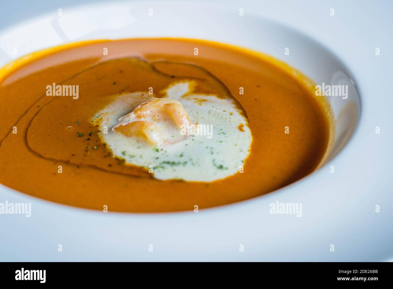 un piatto di bisque di aragosta decorato con un dollop di crema e piccoli gamberetti Foto Stock