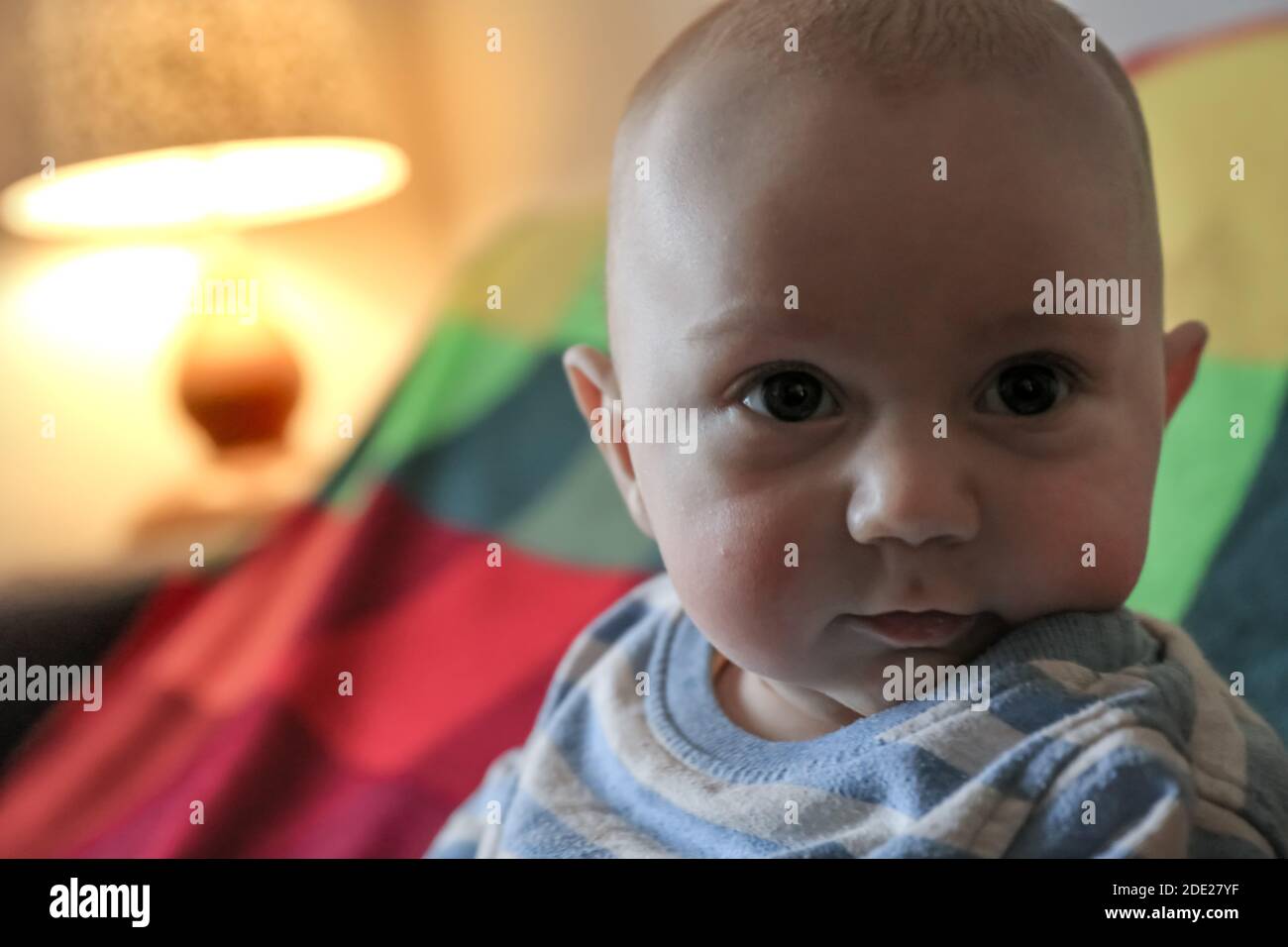 Bambino di tre mesi sulla coperta colorata guardando la macchina fotografica. Vista frontale Foto Stock