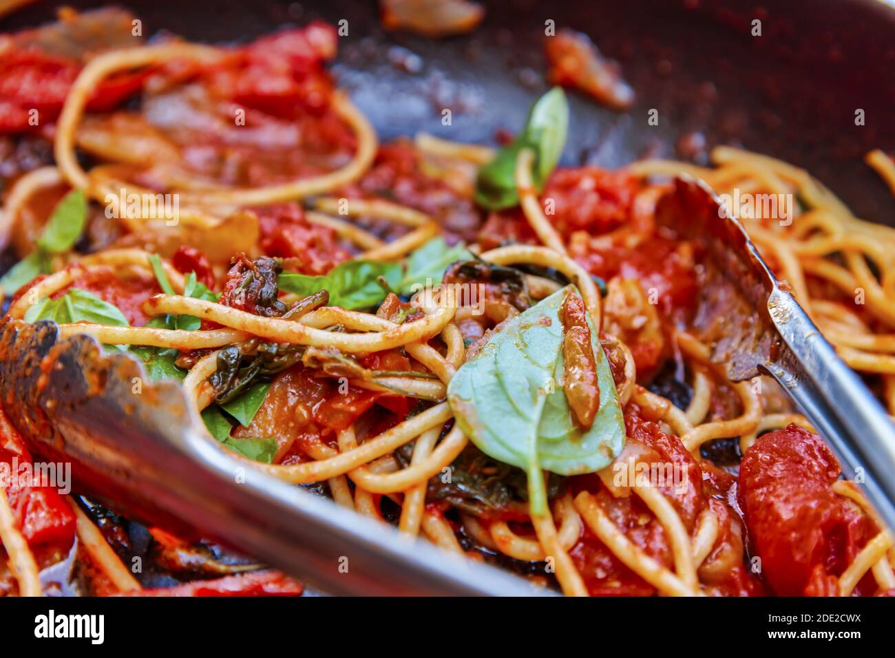 Un pasto rustico preparato con spaghetti appena cotti, pomodoro piccante e basilico verde profumato. Preparati rapidamente a condividere con la famiglia e gli amici. Foto Stock