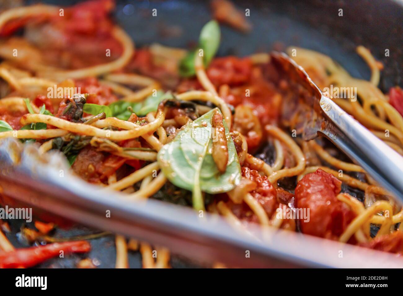 Un pasto rustico preparato con spaghetti appena cotti, pomodoro piccante e basilico verde profumato. Preparati rapidamente a condividere con la famiglia e gli amici. Foto Stock