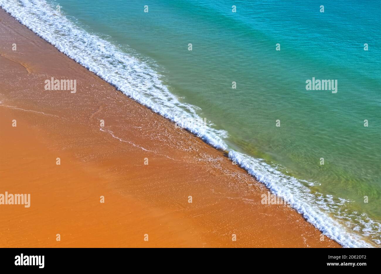 Vista aerea dell'oceano incontra la spiaggia con sabbia rossa e. acqua turchese Foto Stock