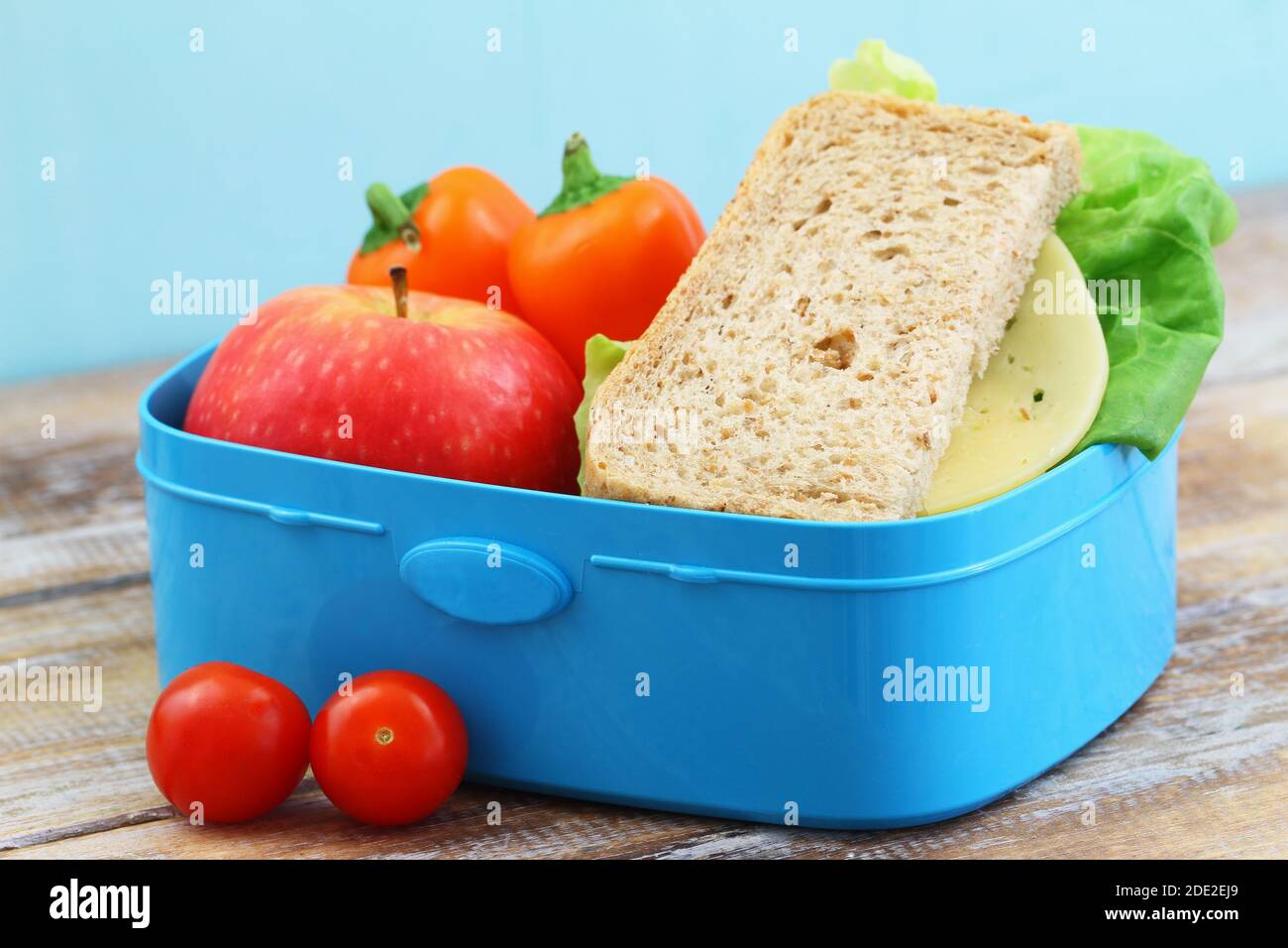Pranzo sano e nutriente a scuola con sandwich di formaggio marrone, pepe giallo croccante e mela rossa Foto Stock