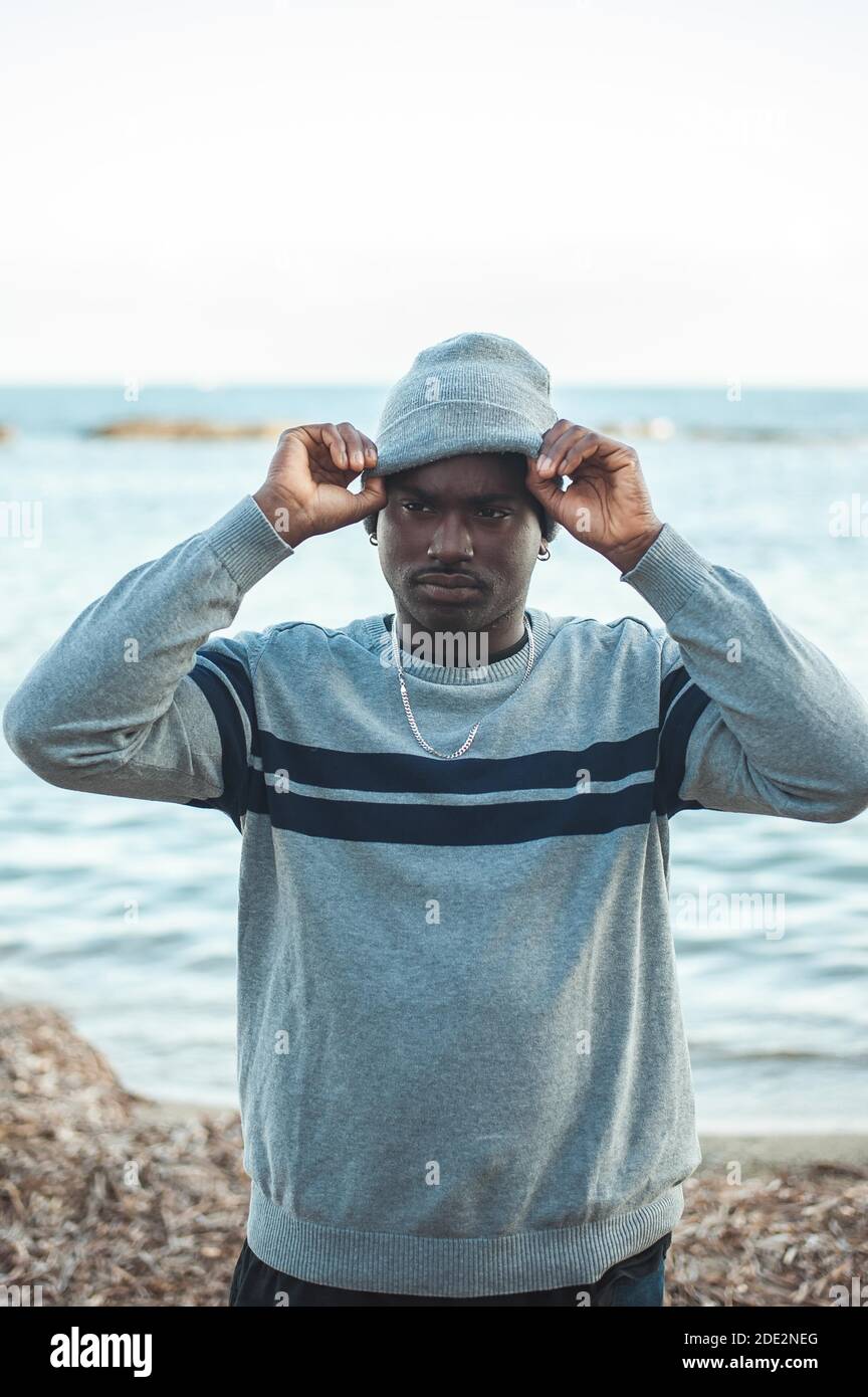 Afro uomo che mette su un cappello invernale. Foto Stock