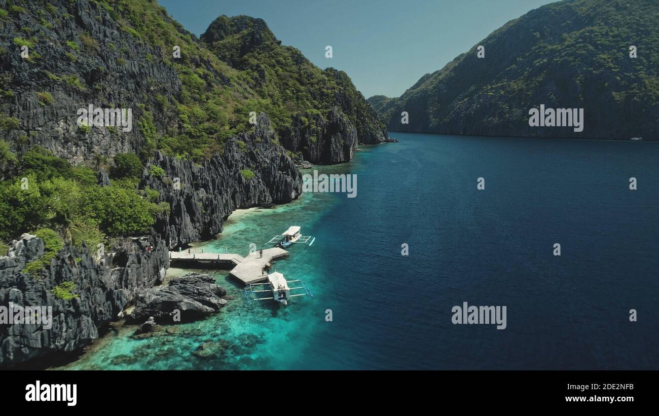 Splendido paesaggio naturale esotico sull'isola di montagna di Palawan, Filippine, Asia. Vista aerea delle barche sulla costa della scogliera dell'oceano con verde foresta tropicale. Drone cinematografico con luce soffusa Foto Stock