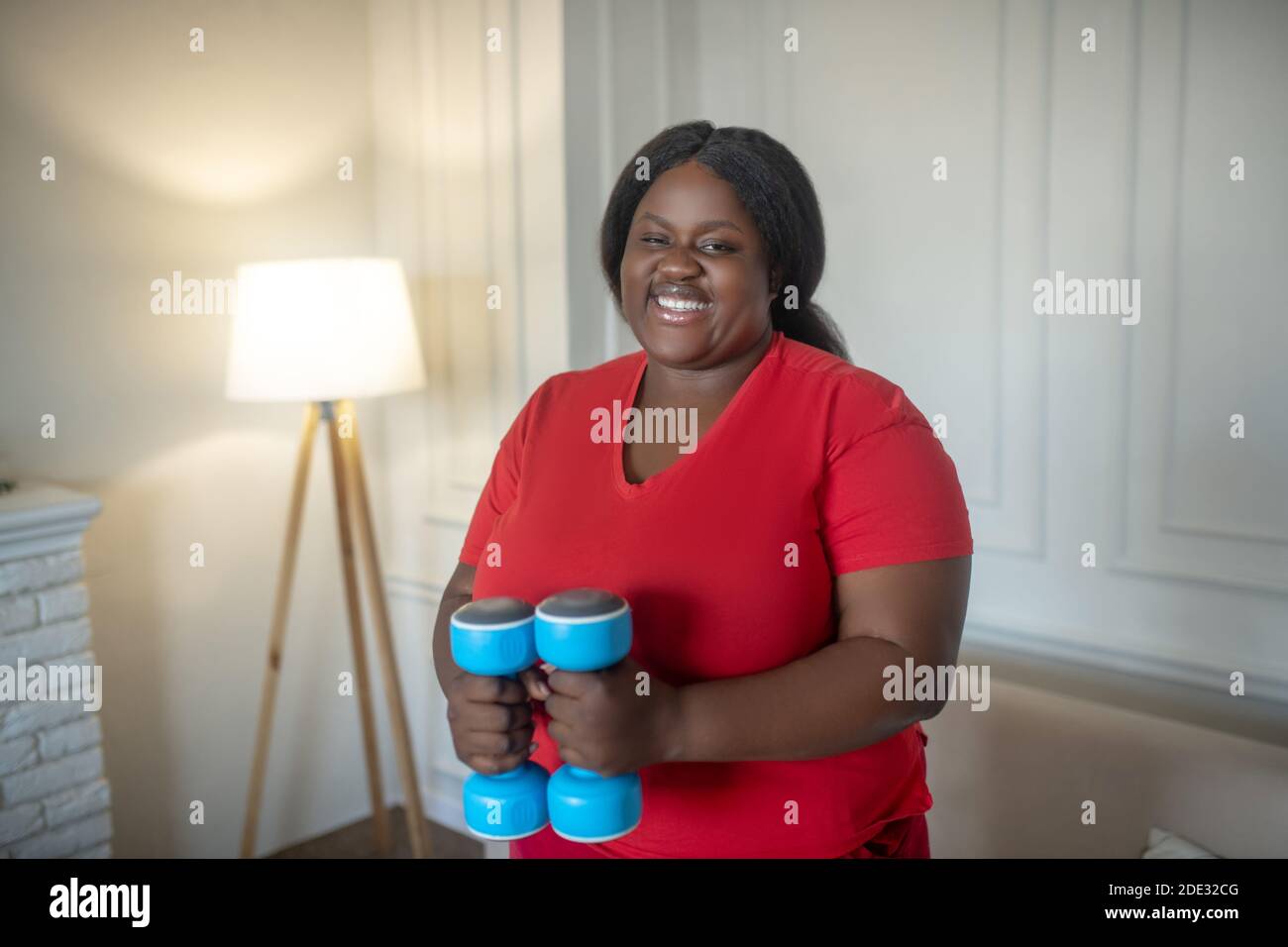 Più taglia donna afroamericana che ha un workout con i manubri Foto Stock