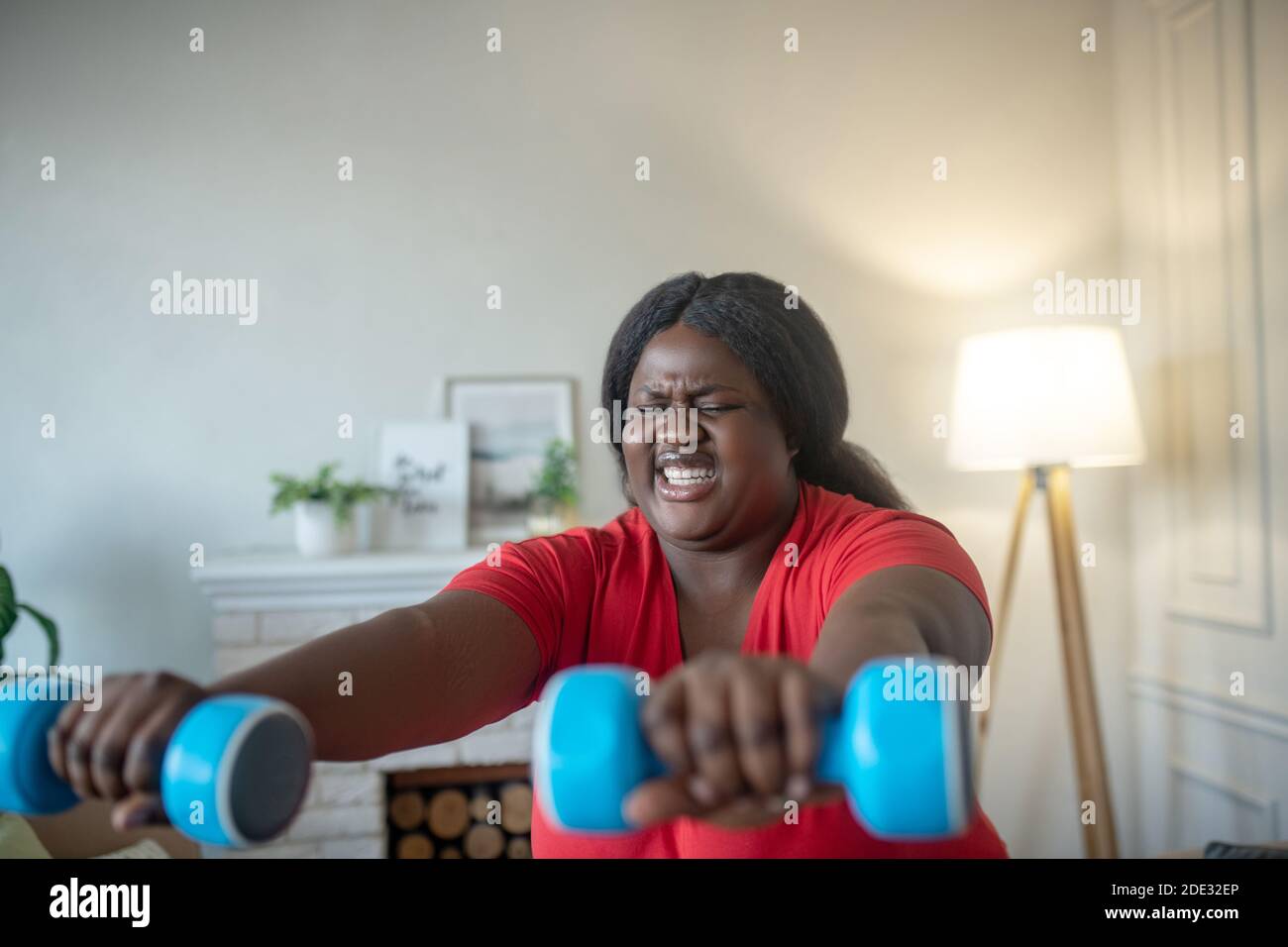 Più taglia donna afroamericana che fa squats con i manubri con tensione Foto Stock