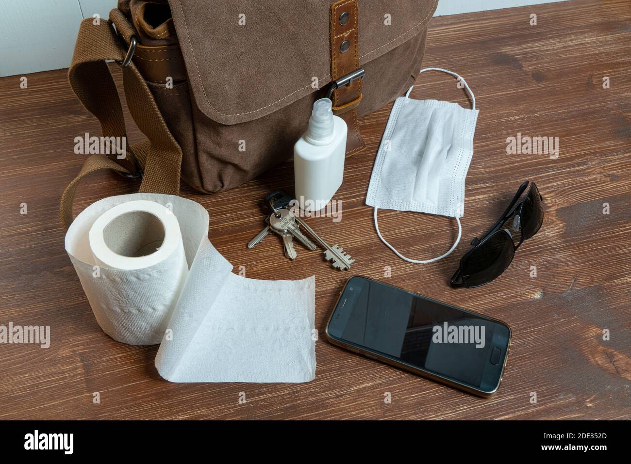 una borsa e alcuni oggetti e un rotolo di gabinetto carta su un tavolo di legno Foto Stock