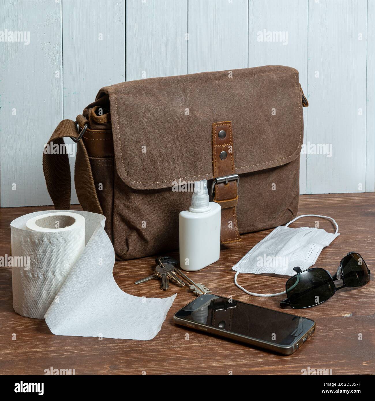 una borsa e alcuni oggetti e un rotolo di gabinetto carta su un tavolo di legno Foto Stock