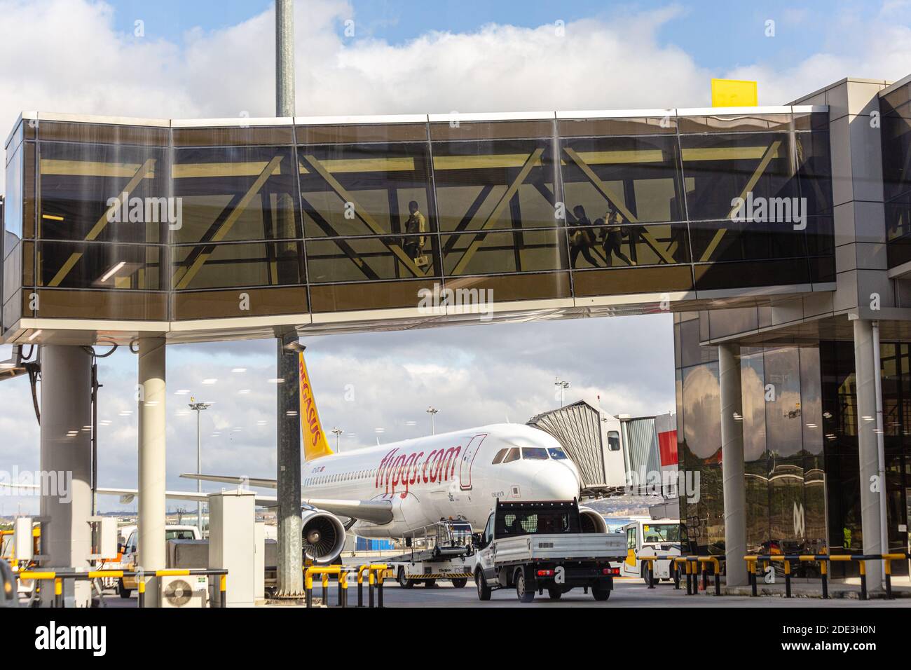 I passeggeri camminano attraverso il ponte di imbarco passeggeri nel terminal dell'aeroporto. Un aereo sullo sfondo. Aeroporto Sabiha Gokcen. Foto Stock