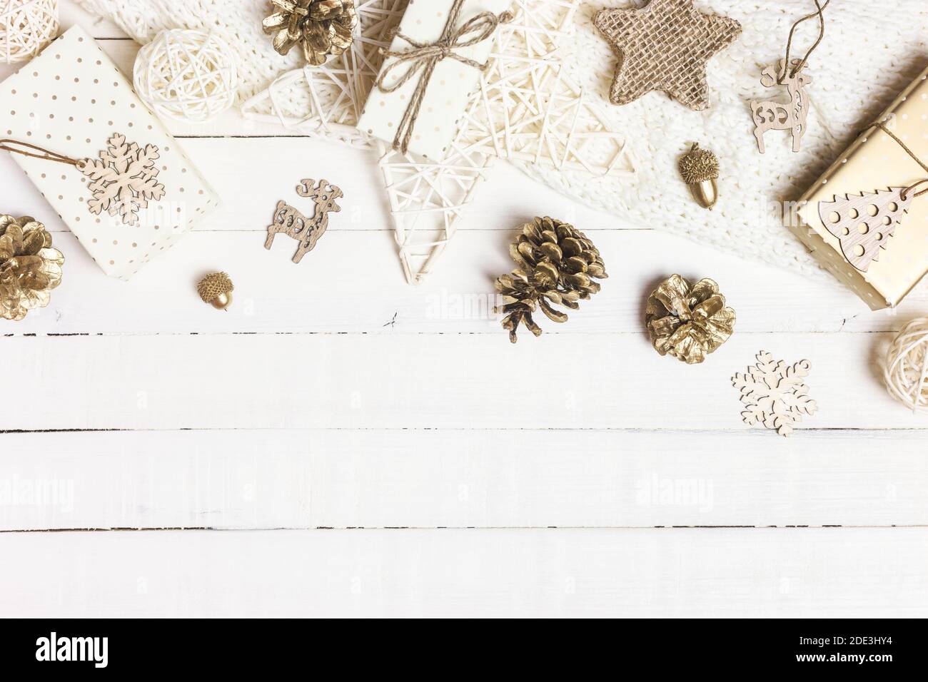 Composizione natalizia o invernale. Regali di Natale, coni di pino, coperta a maglia e ornamenti su sfondo bianco di legno. Disposizione piatta, vista dall'alto, spazio per la copia Foto Stock
