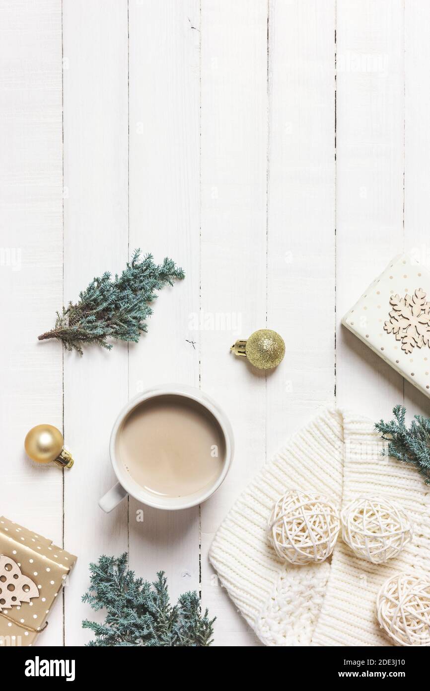 Accoglienti momenti mattutini a casa con una tazza di caffè, una coperta calda, un albero sempreverde e ornamenti su sfondo di legno bianco. Inverno, concetto di vacanza. Piatto Foto Stock