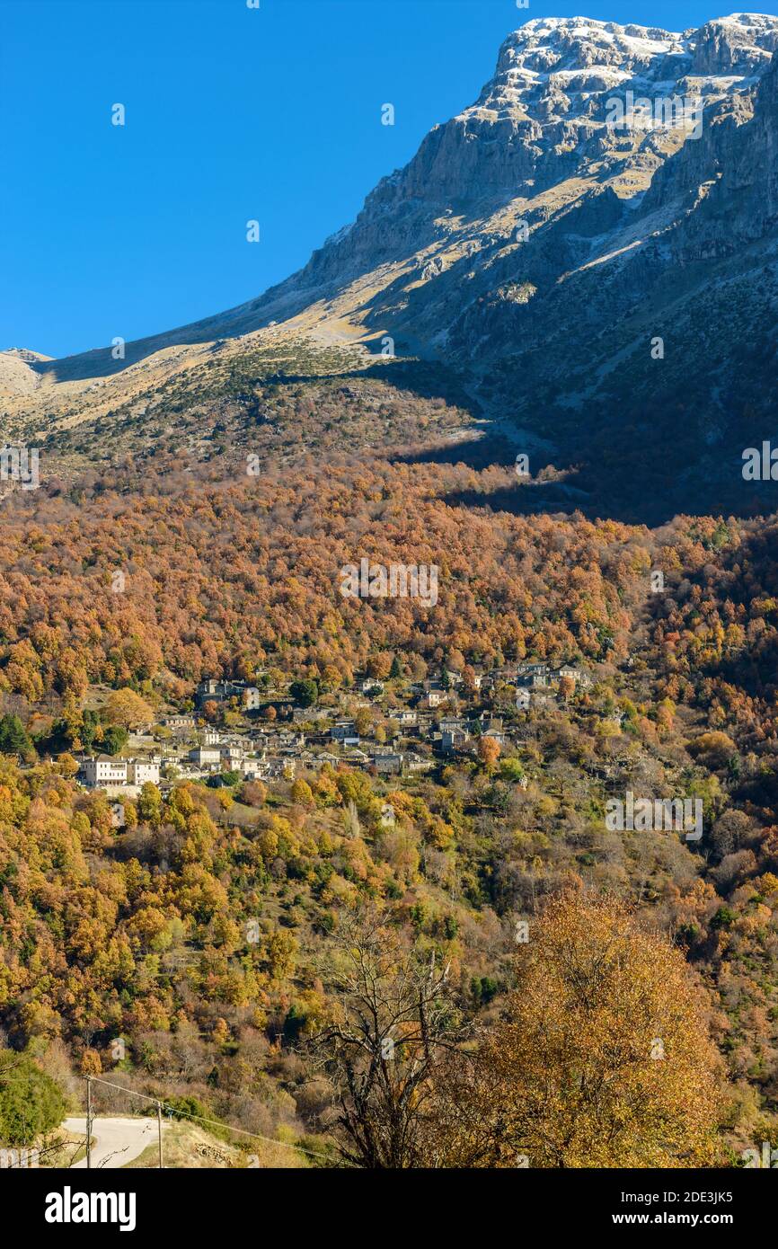 Vista del villaggio tradizionale Mikro Papigo con pietra edifici e astraka montagna come sfondo durante la stagione autunnale in zagori Grecia Foto Stock