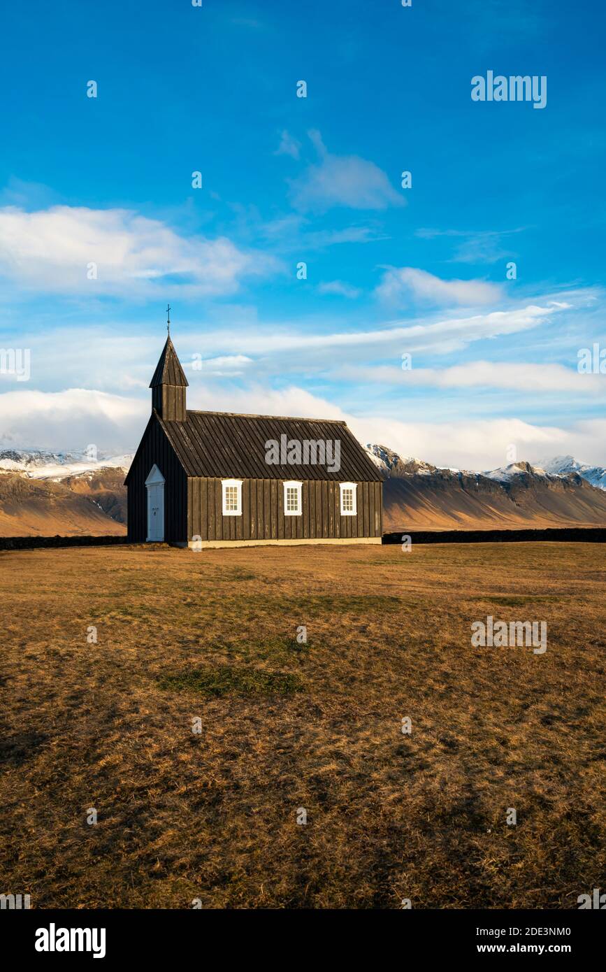 Chiesa di Budakirkja in legno nero contro le montagne innevate, Budir, Penisola di Snaefellsness, Islanda Foto Stock