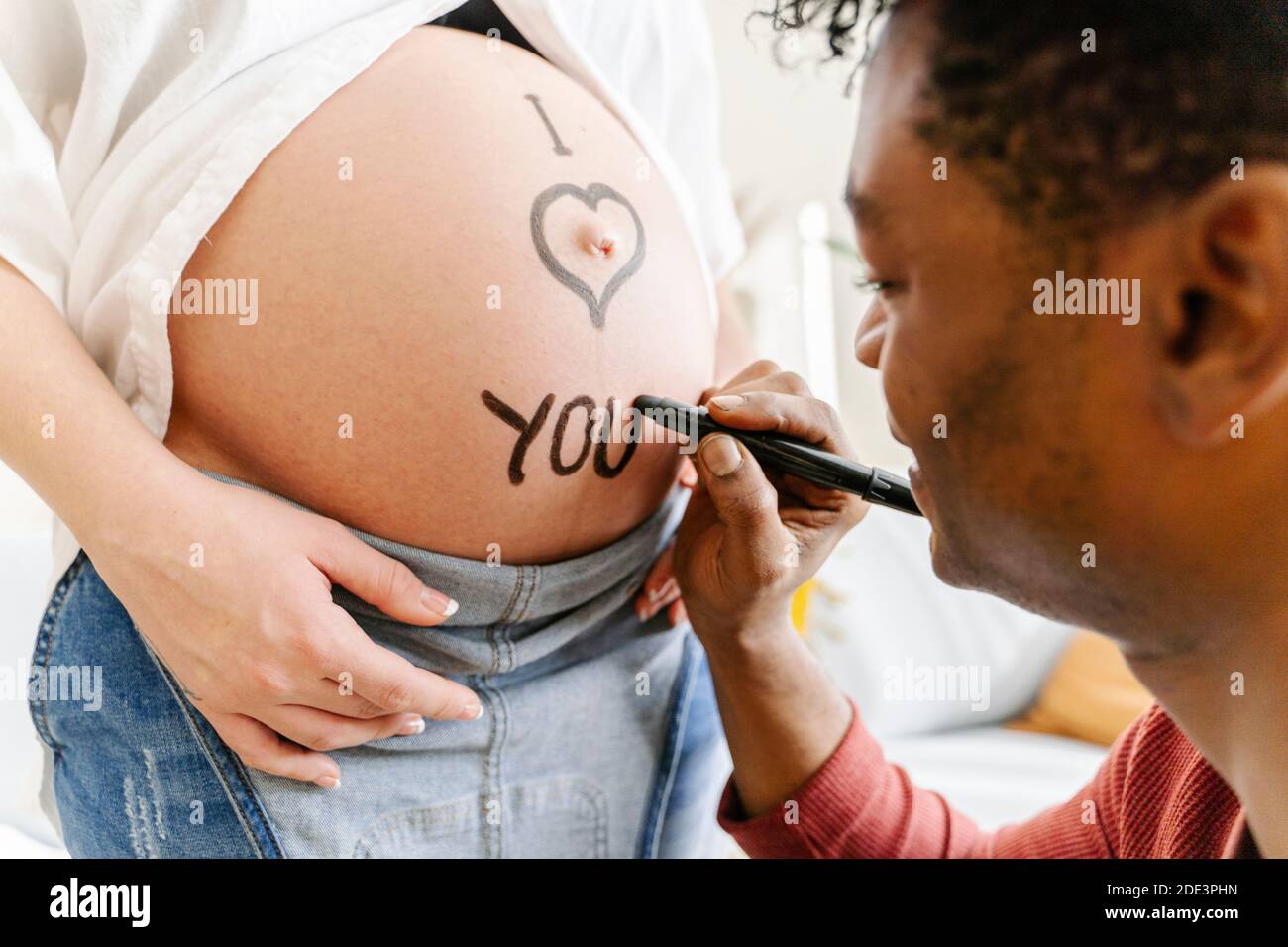 Marito disegnando la frase ti amo sul ventre della sua moglie incinta. Concetto di genitorialità Foto Stock