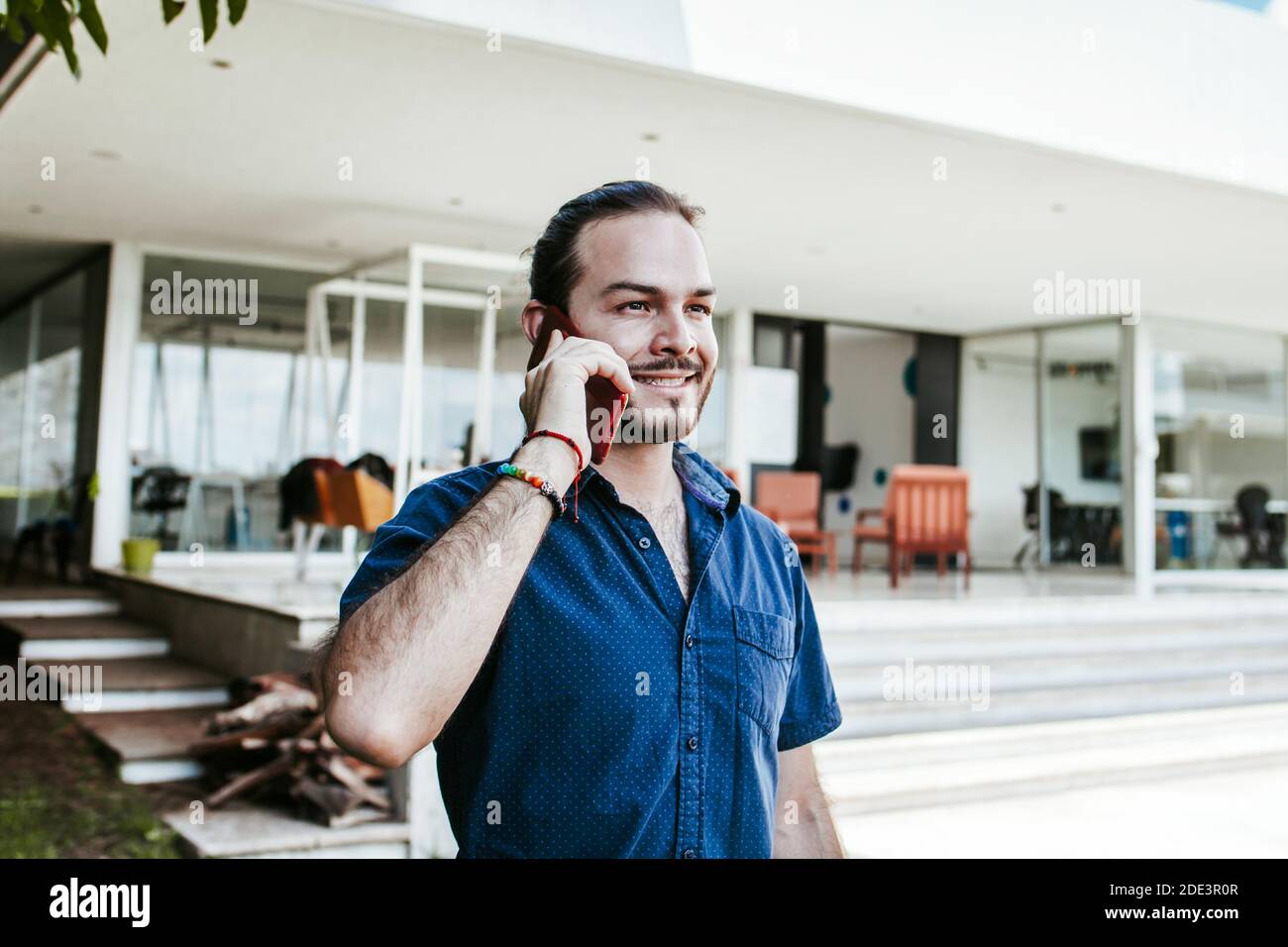 Giovane uomo d'affari latino che cammina e parla al telefono cellulare all'aperto In Messico Foto Stock