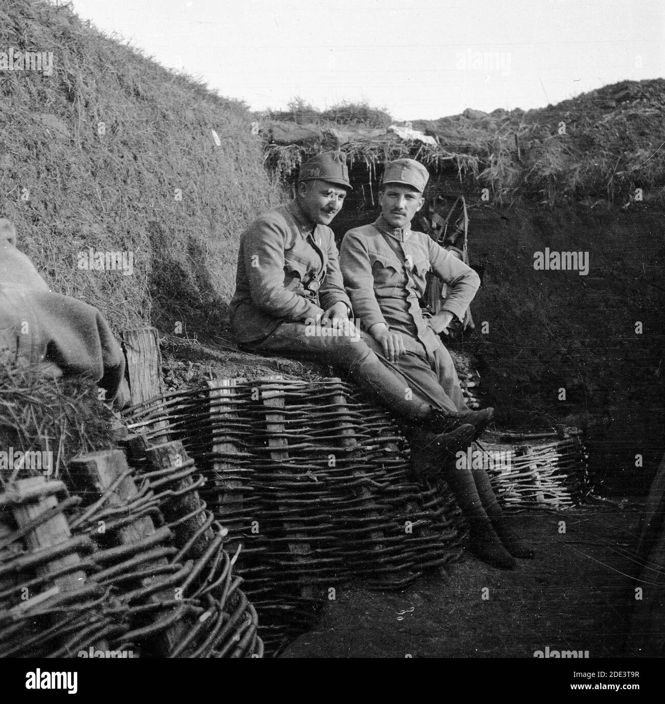 Esercito austro-ungarico durante la prima guerra mondiale. Due soldati che riposano, uno dei quali sorridente, in uniformi austriache seduti in una trincea di streghe rinforzate da lavori di bastone. Data e luogo esatti incerti. Foto Stock