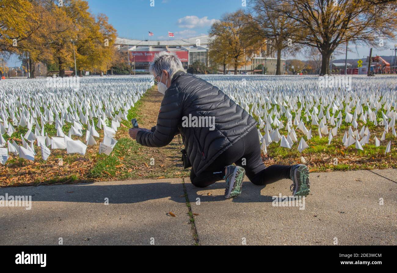Washington DC, 28 novembre 2020, USA: Una donna scatta una foto al telefono cellulare di una delle centinaia di migliaia di piccole bandiere bianche che rappresentano la gente che h Foto Stock