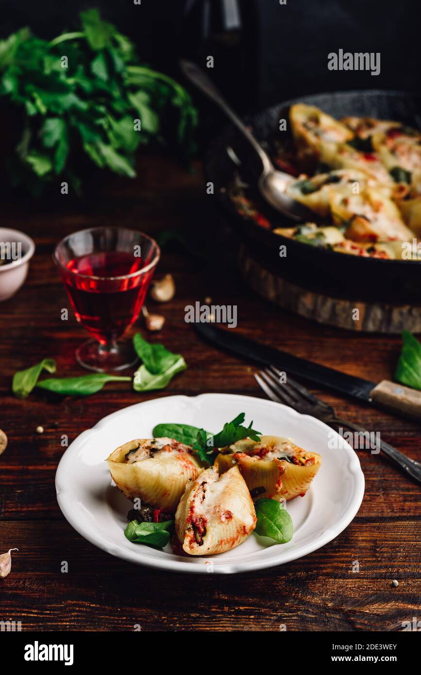 Conchiglie di jumbo al forno farcite con manzo macinato, spinaci e formaggio su piatto bianco Foto Stock