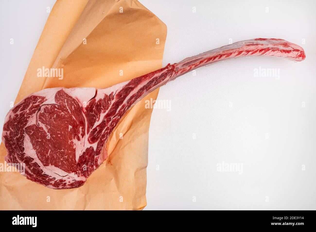 Bistecca di tomahawk ribeye tagliata di fresco con carta di macellaio su un bancone di carne Foto Stock