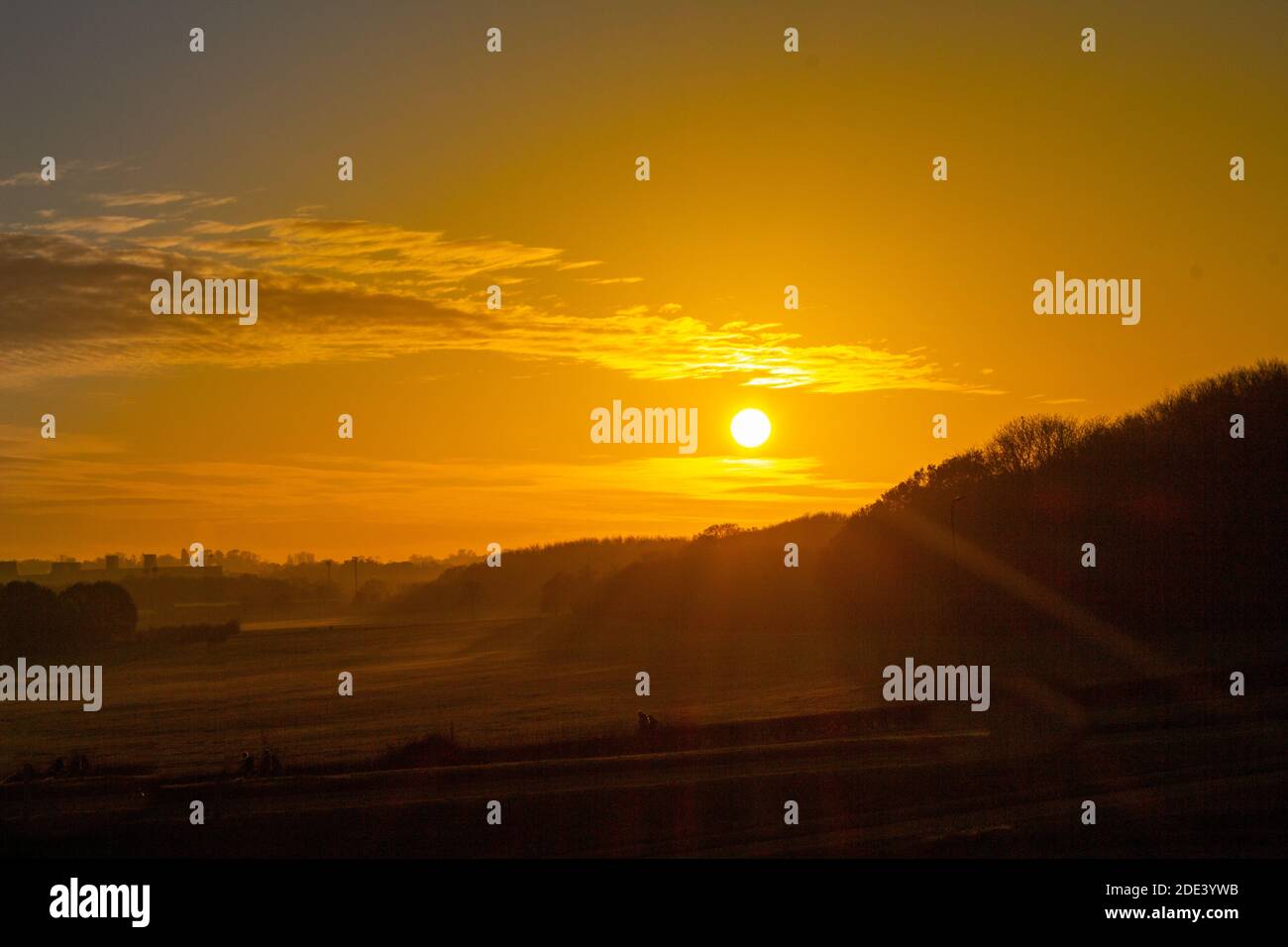 Tramonto sulle colline vicino a un bosco nel Hertfordshire, scenico arancio e rosso sole con nuvole al tramonto in una fredda giornata d'autunno, natura panoramica Foto Stock