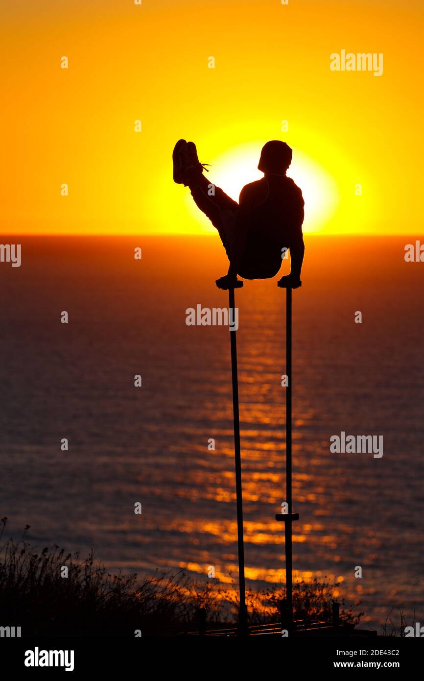 Un ginnasta esegue un v-sit mentre si silhouette contro il tramonto a Black's Beach, San Diego, CA. Foto Stock
