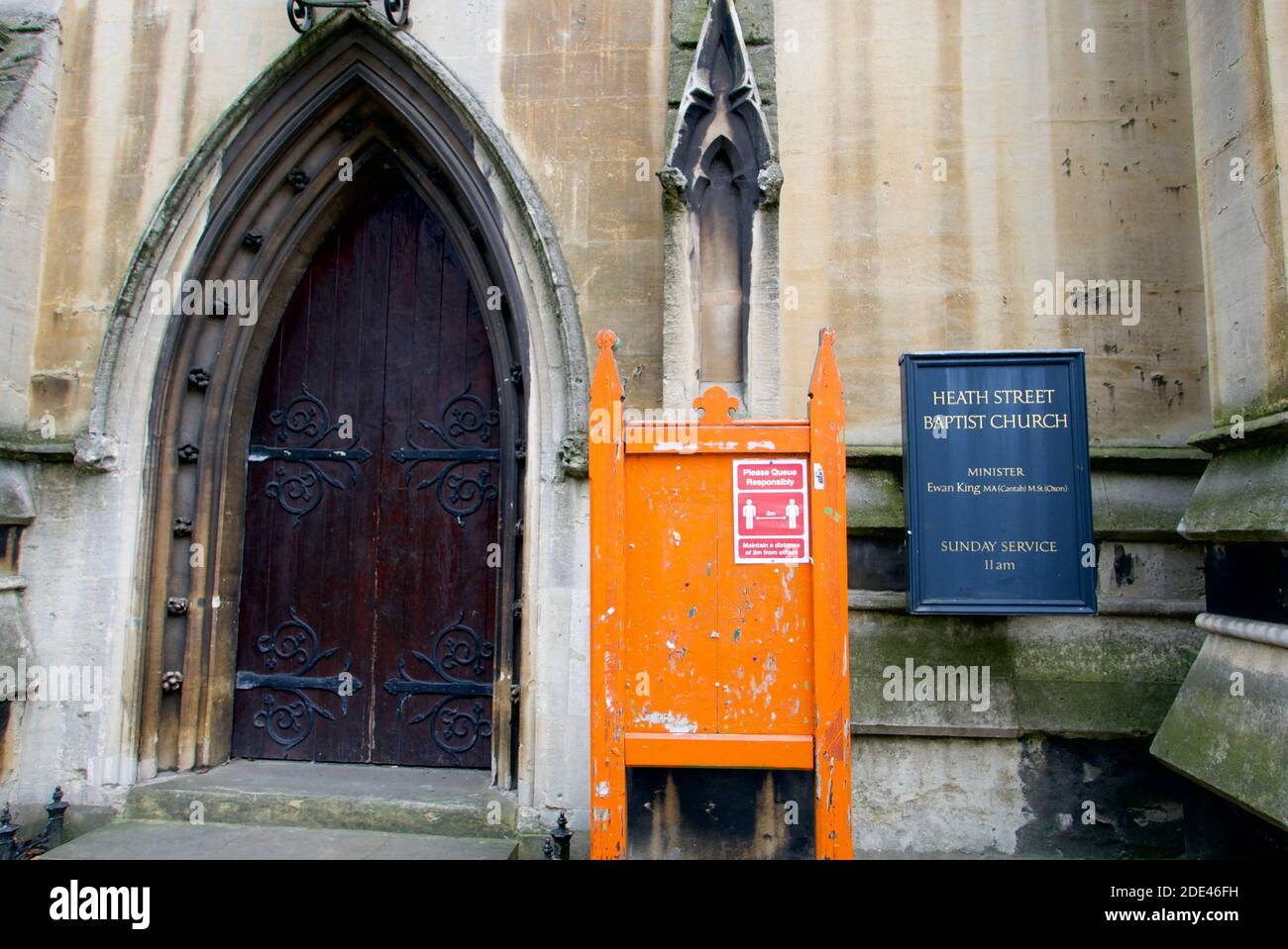 Ingresso alla Chiesa Battista di Heath Street nel Villaggio di Hampstead, Londra, con una bacheca arancione vuota che mostra solo il simbolo del Covid19 di allontanamento sociale. Foto Stock