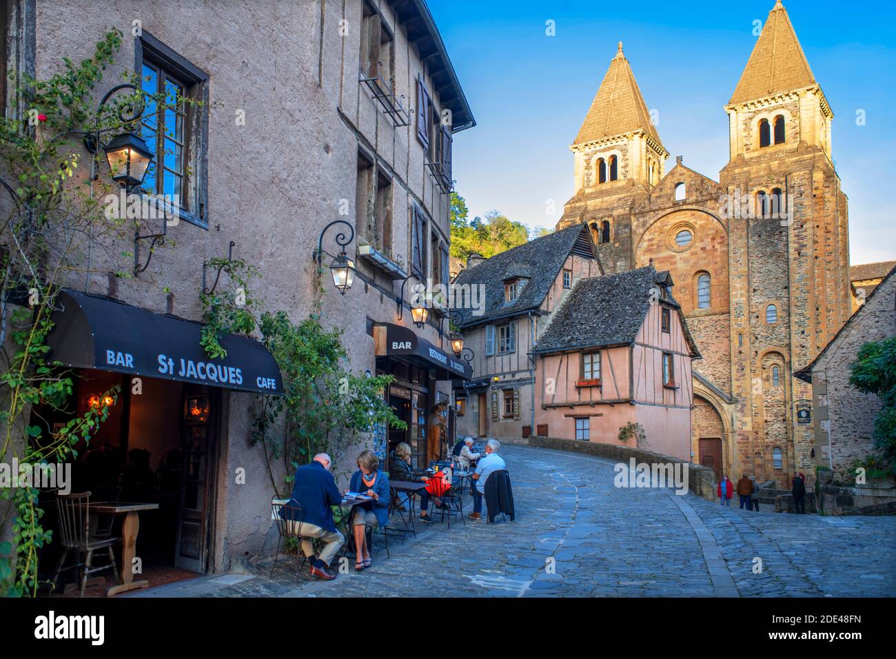 Il piccolo borgo medievale di Conques in Francia. Mostra ai visitatori la sua abbazia-chiesa e case cluster sormontate da tetti di ardesia. Attraversamento di strada stretta Foto Stock