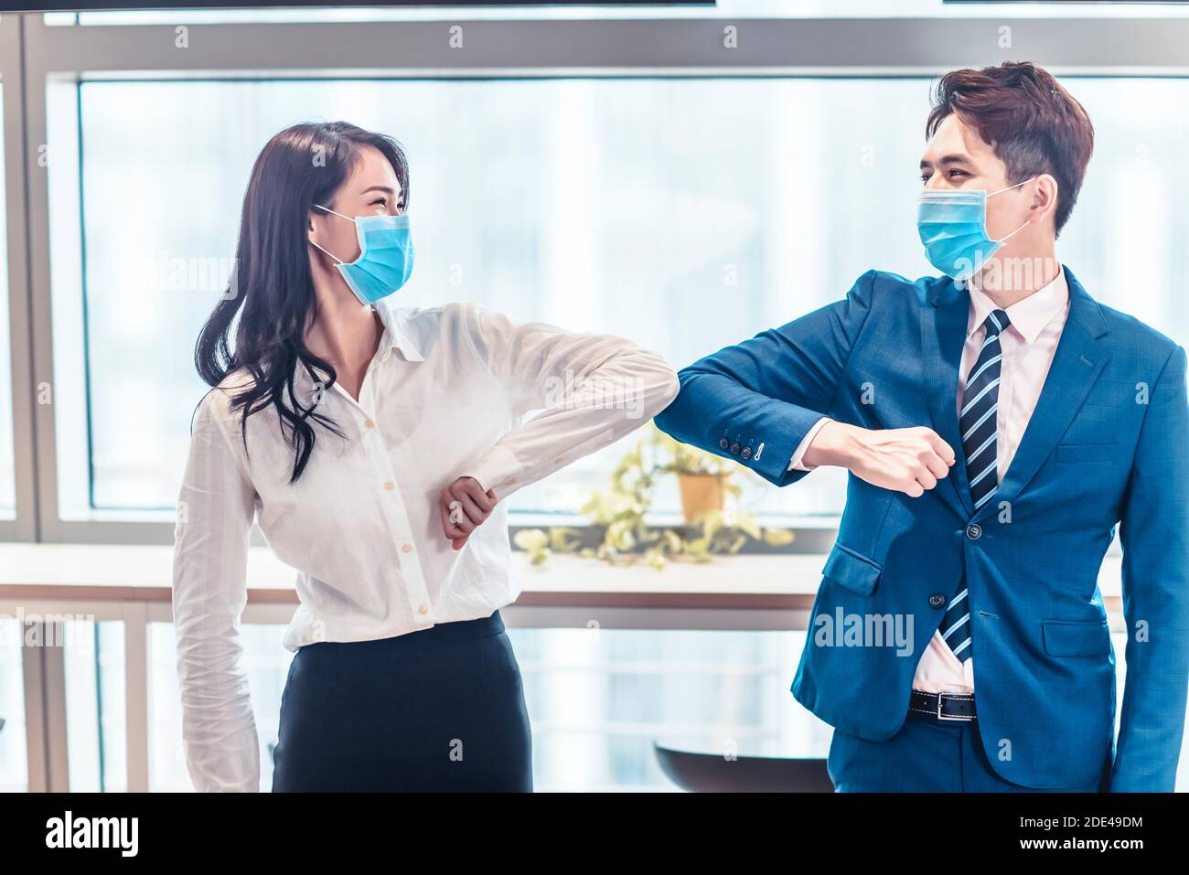 uomini d'affari che indossano una maschera medica e colpiscono con i loro gomiti invece di handshake Foto Stock