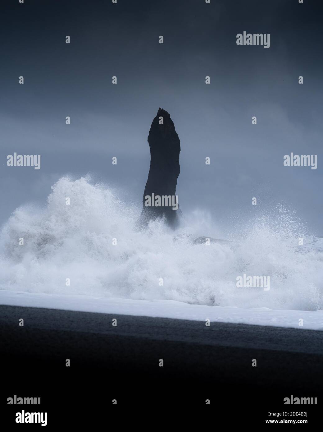 Forte roccia con forti onde infrangenti su una spiaggia vulcanica, Vik, Islanda Foto Stock