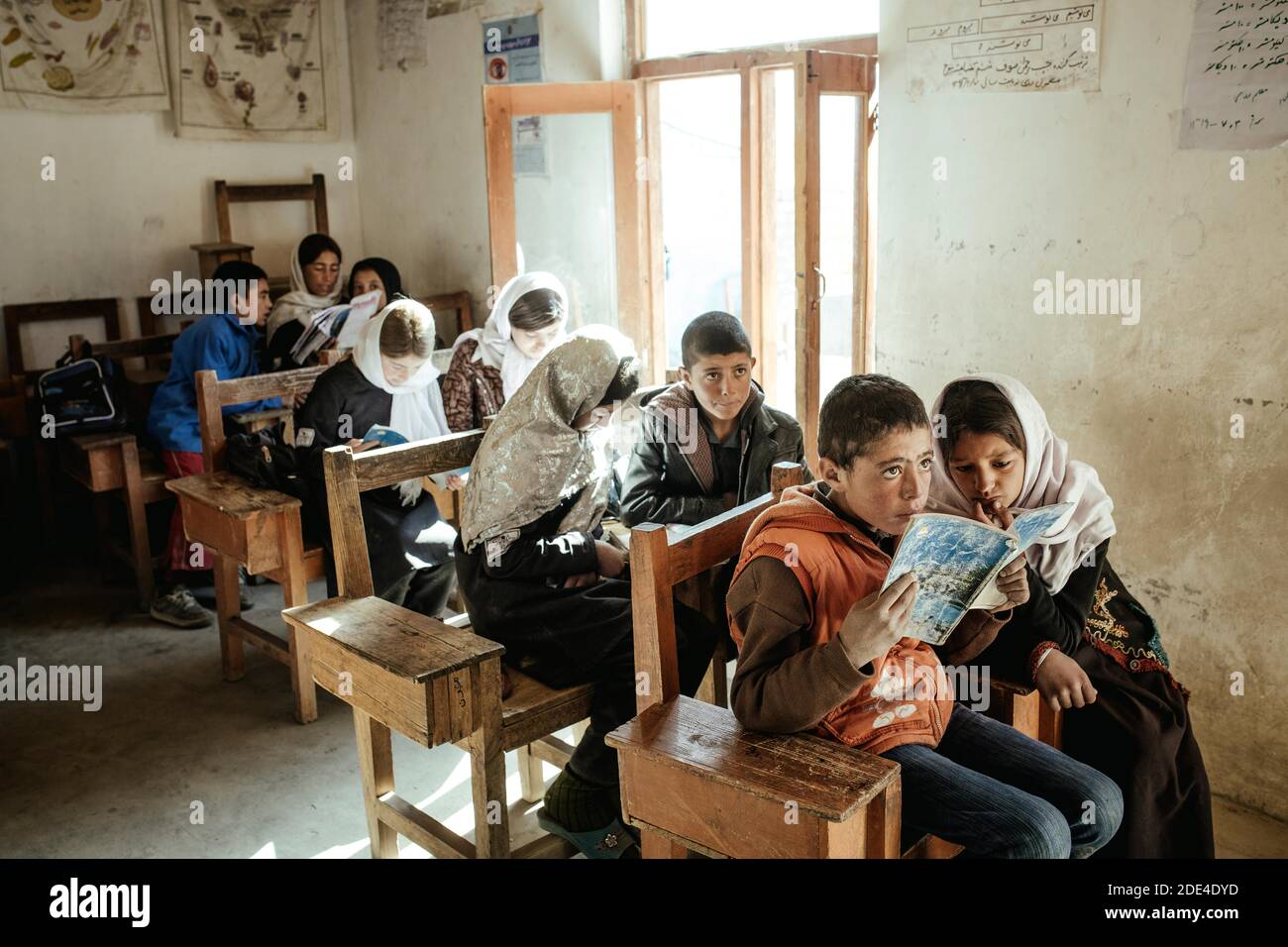 Bambini in classe, una ragazza e un ragazzo che leggono insieme da un libro di esercizi, Potokh Primary School, Potokh, Wakhan Corridor, Afghanistan Foto Stock
