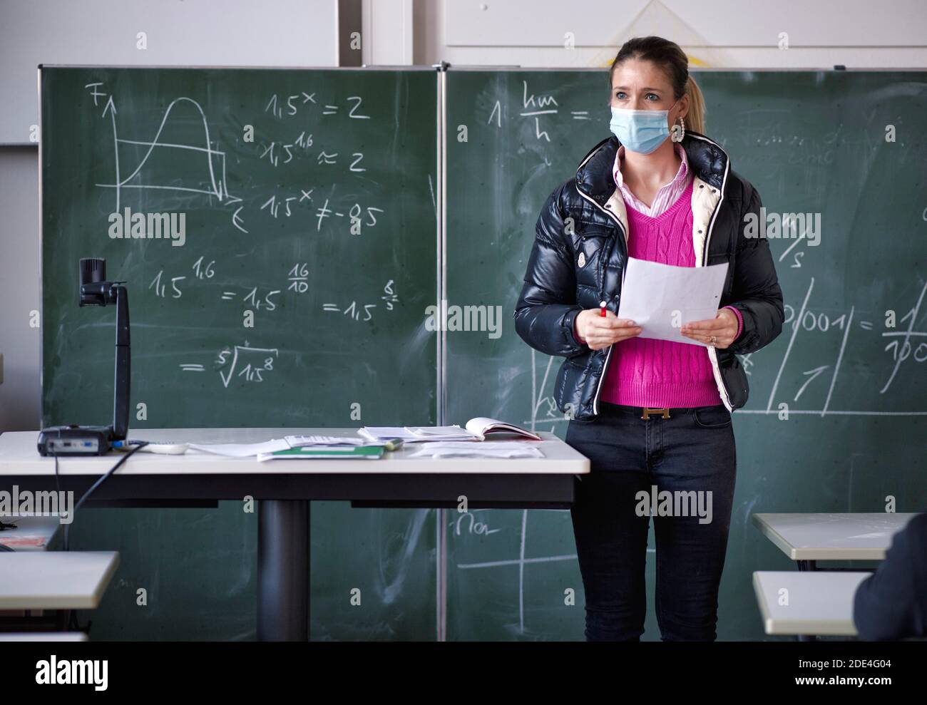 Insegnante con giacca invernale e maschera facciale in aula, gesti, crisi corona, Stoccarda, Baden-Wuerttemberg, Germania Foto Stock