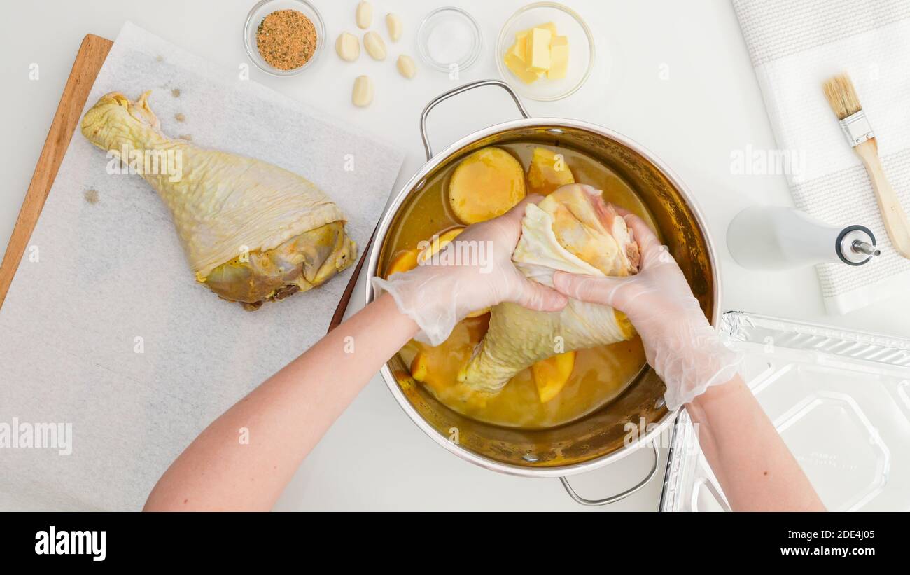 Cosce di tacchino marinate con succo d'arancia, fette d'arancia, aglio e spezie. Ricetta di cosce di tacchino arrosto, processo di preparazione passo dopo passo. Foto Stock