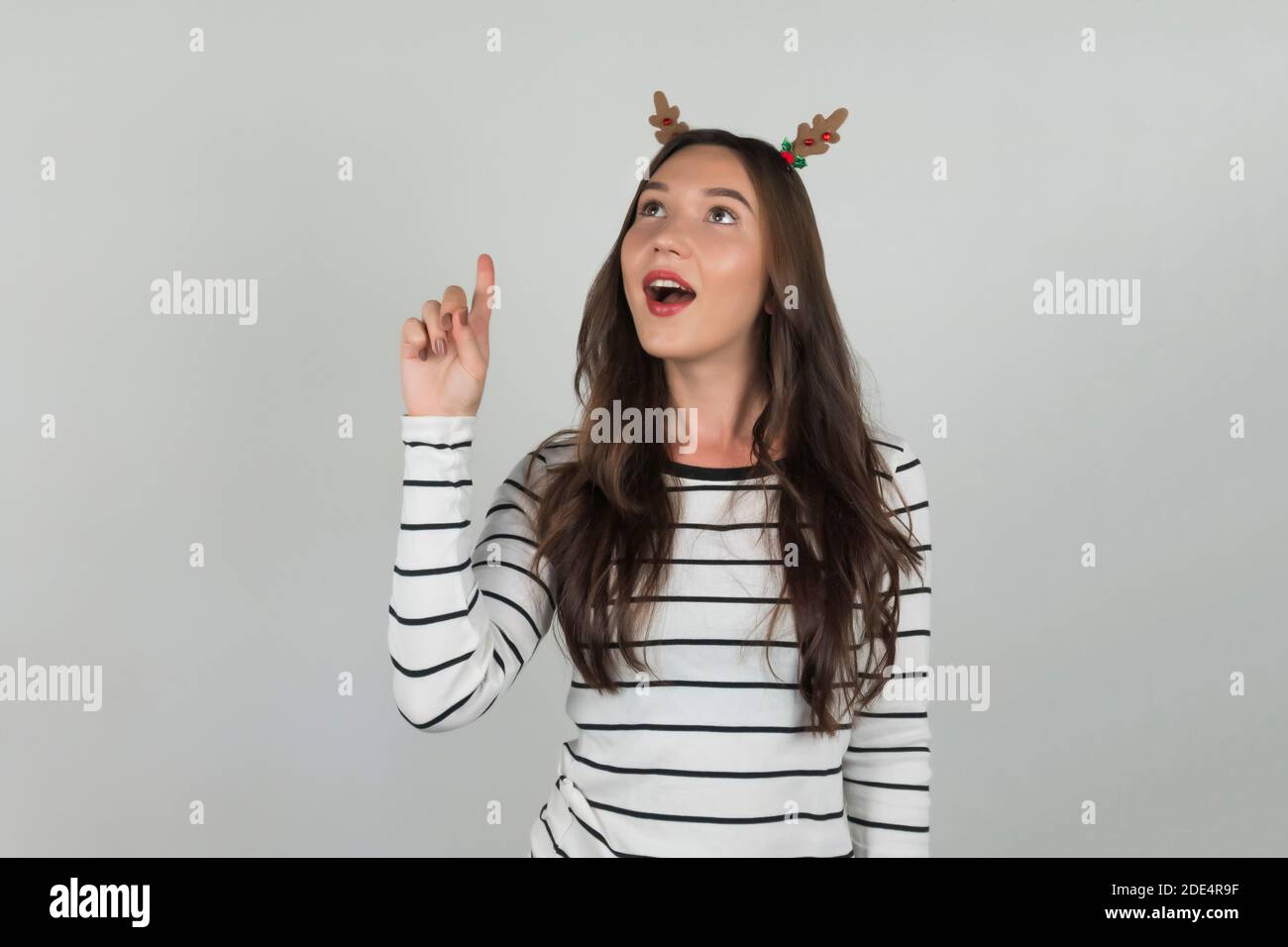 Una donna con le decorazioni di Natale nei suoi capelli sta pensando ad un'idea di festa. Foto di alta qualità Foto Stock