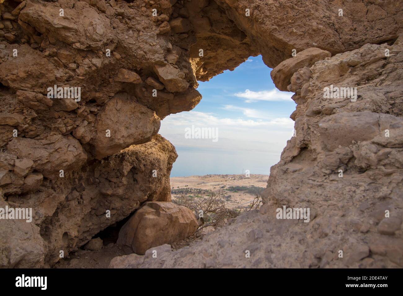 Roccia cava a Ein Gedi, sullo sfondo dei palmeti, il Mar Morto e la strada n° 90. Israele. Foto Stock