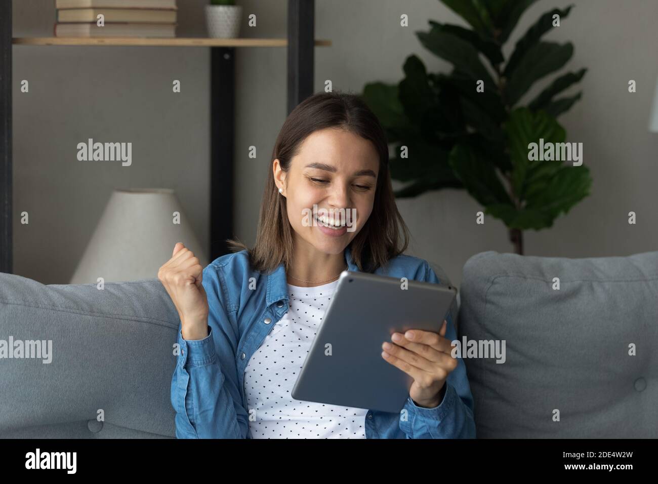 Donna molto gioiosa eccitata con un buon affare su tablet Foto Stock