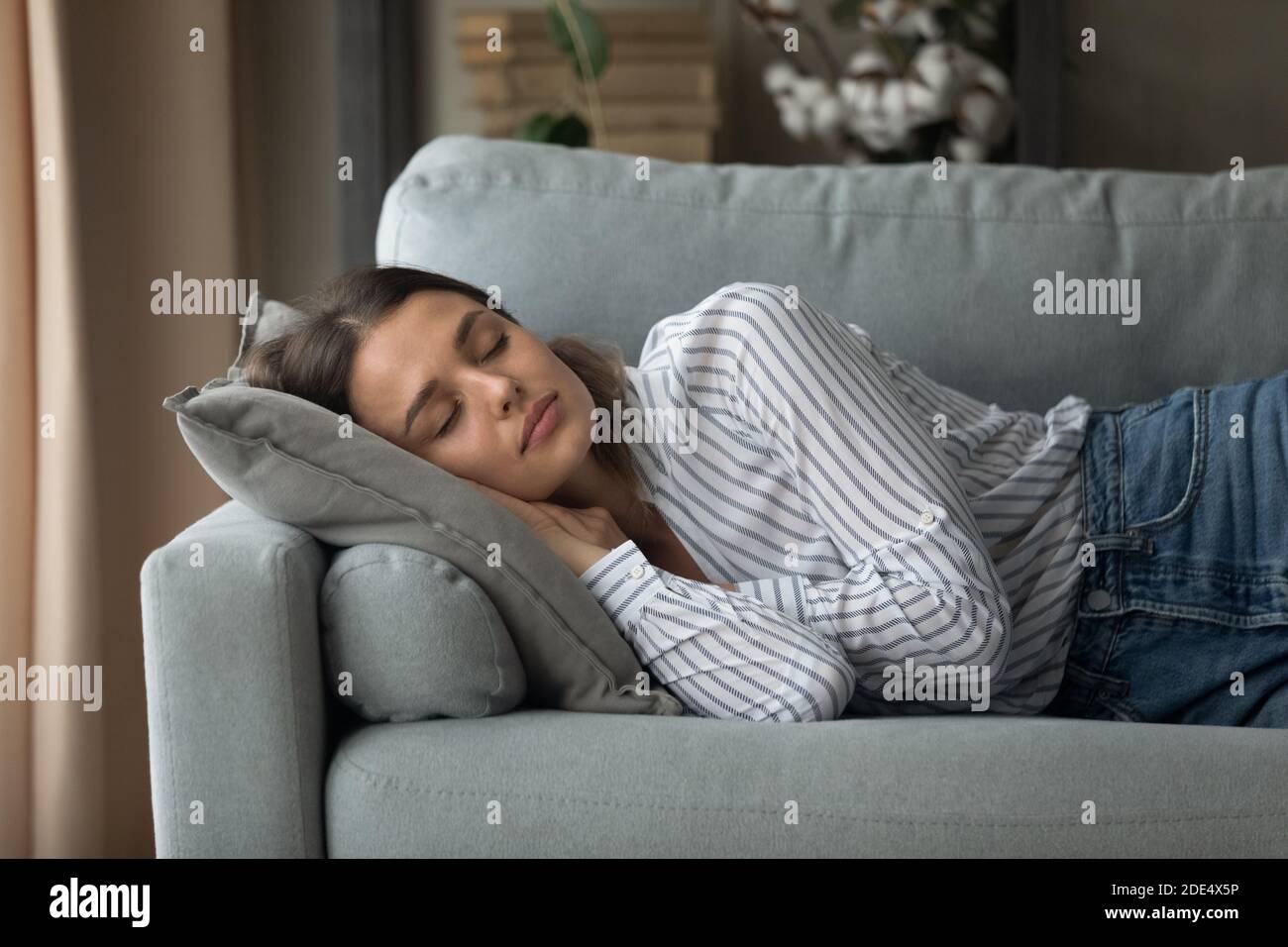 Calma giovane donna che dorme sul divano a casa Foto Stock