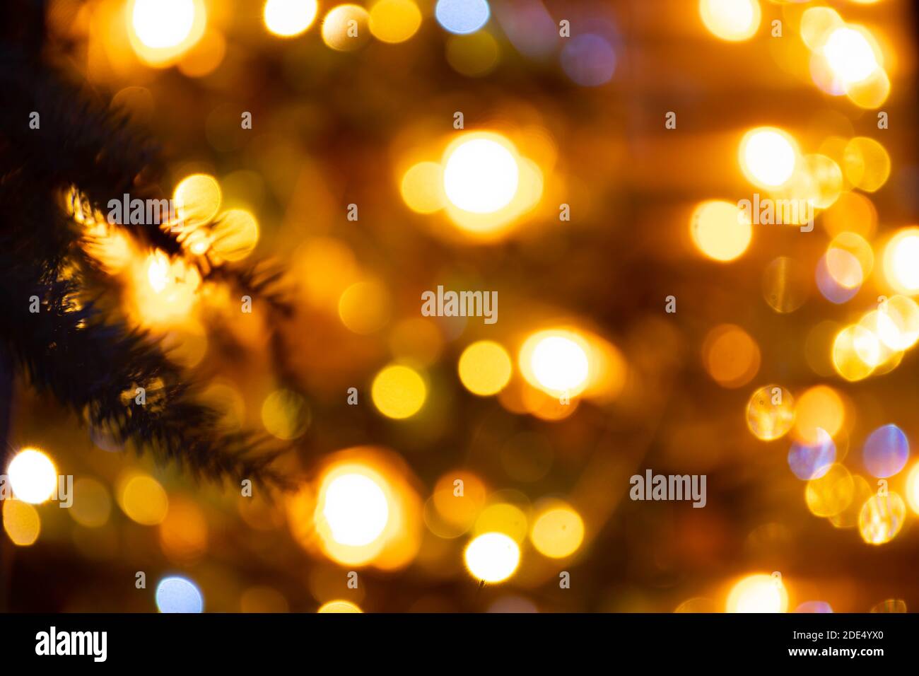 Astratto sfondo giallo bokeh luci e rami di un albero in inverno, sfondo di Natale, accogliente e sentimenti caldi Foto Stock