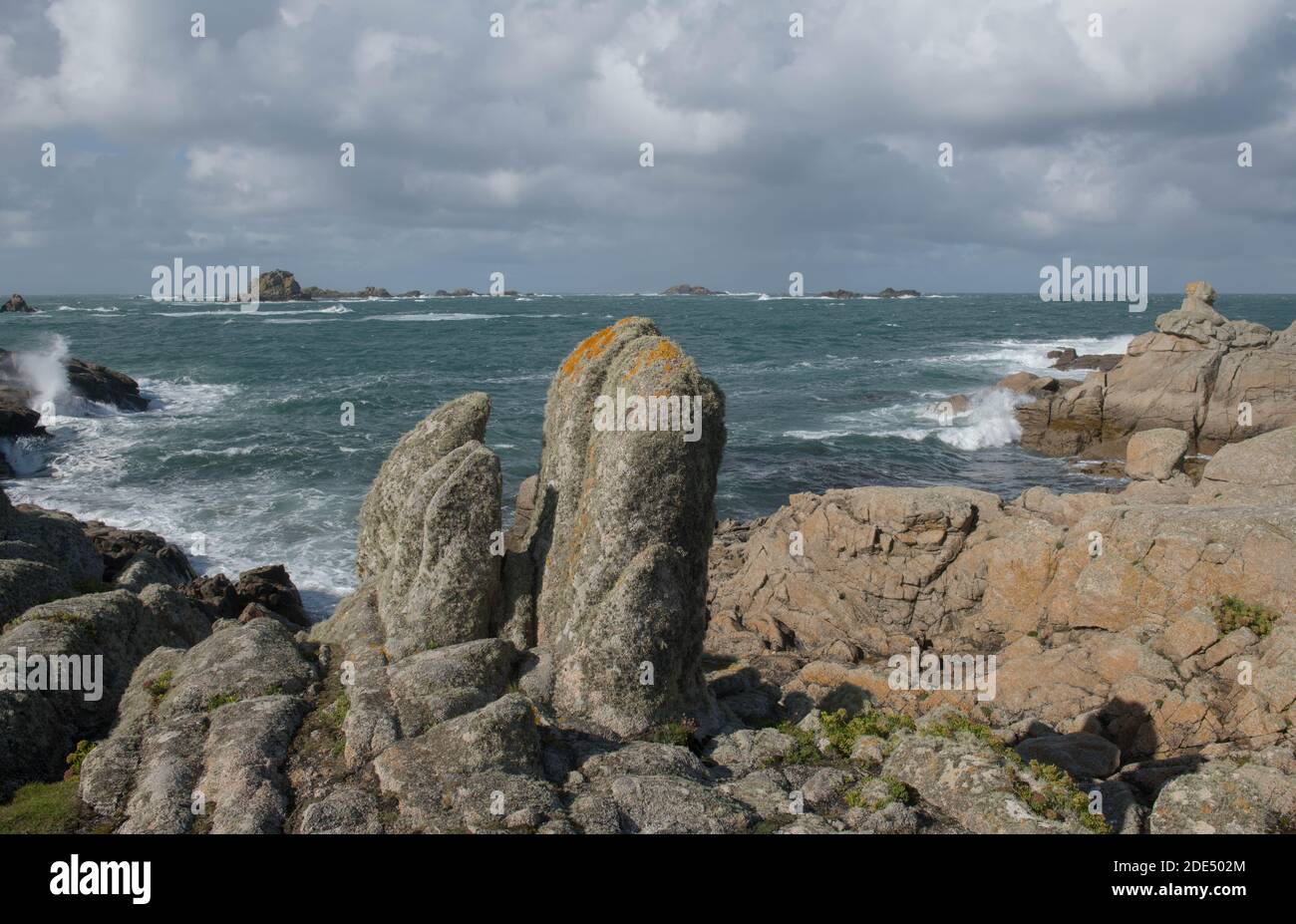 Massi di granito sulla costa con un cielo blu nuvoloso e il mare ruvido sfondo sull'isola di Bryher nelle isole di Scilly, Inghilterra, Regno Unito Foto Stock