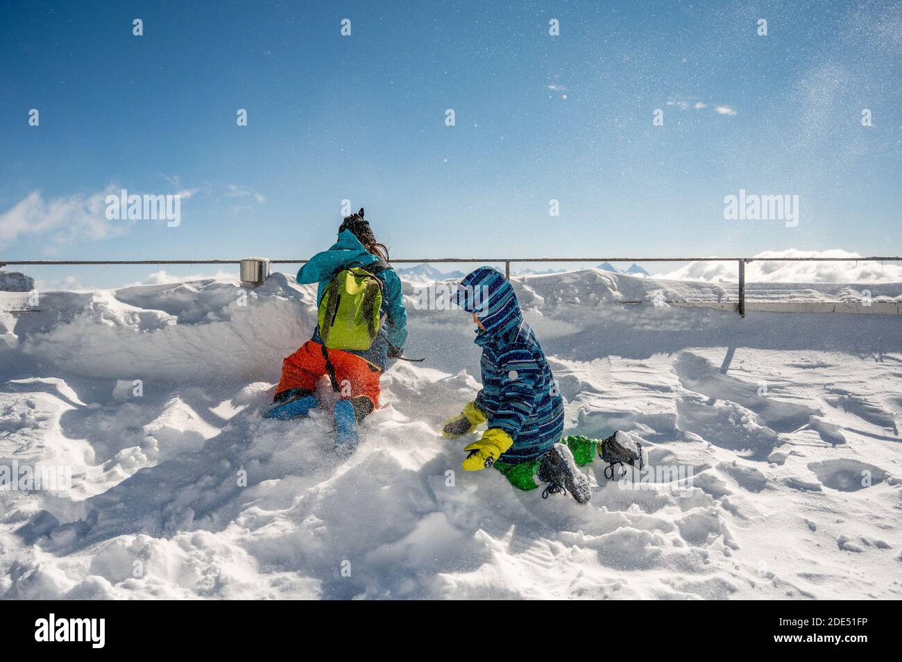 Vista posteriore di due bambini che giocano con la neve sulla cima della montagna. Vacanze invernali con bambini nelle Alpi. Glacier 3000, les Diablerets, Svizzera. Foto Stock