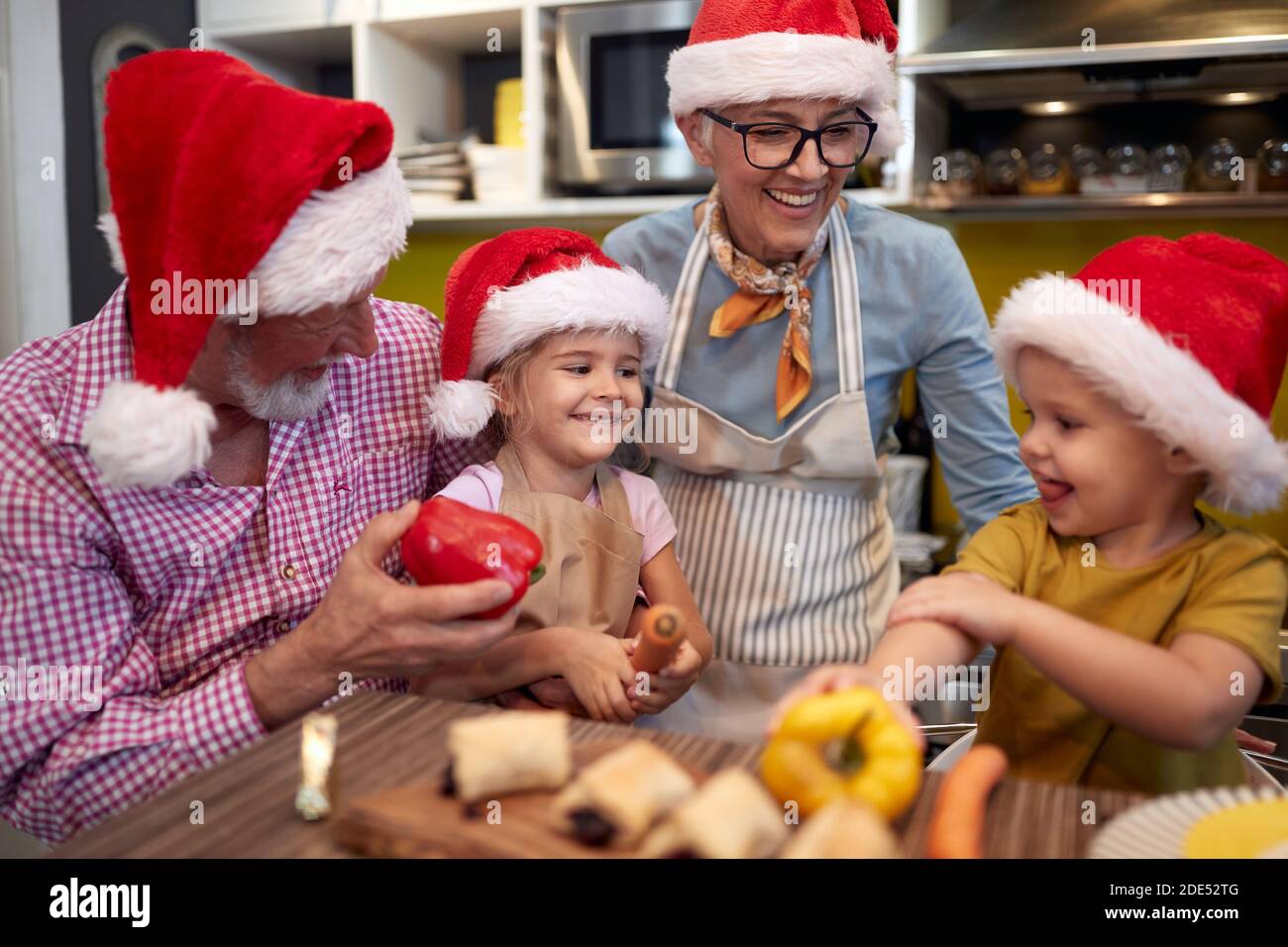 Nonno, nonna e nipoti in cucina insieme in un'atmosfera allegra che prepara le verdure per un pasto di Natale. Natale, famiglia, insieme Foto Stock