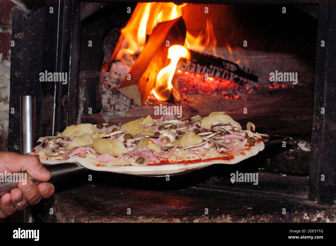 lo chef pizzeria infila la pizza nel forno a legna caldo Foto Stock