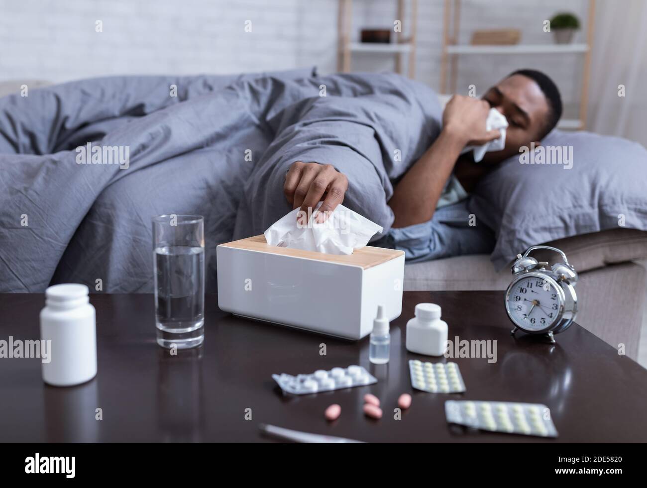 Malato African American Man starnuti avendo sinusite a casa Foto Stock