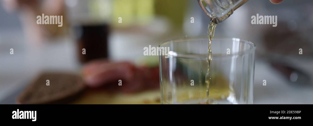 La mano femminile versa il liquore in un bicchiere Foto Stock