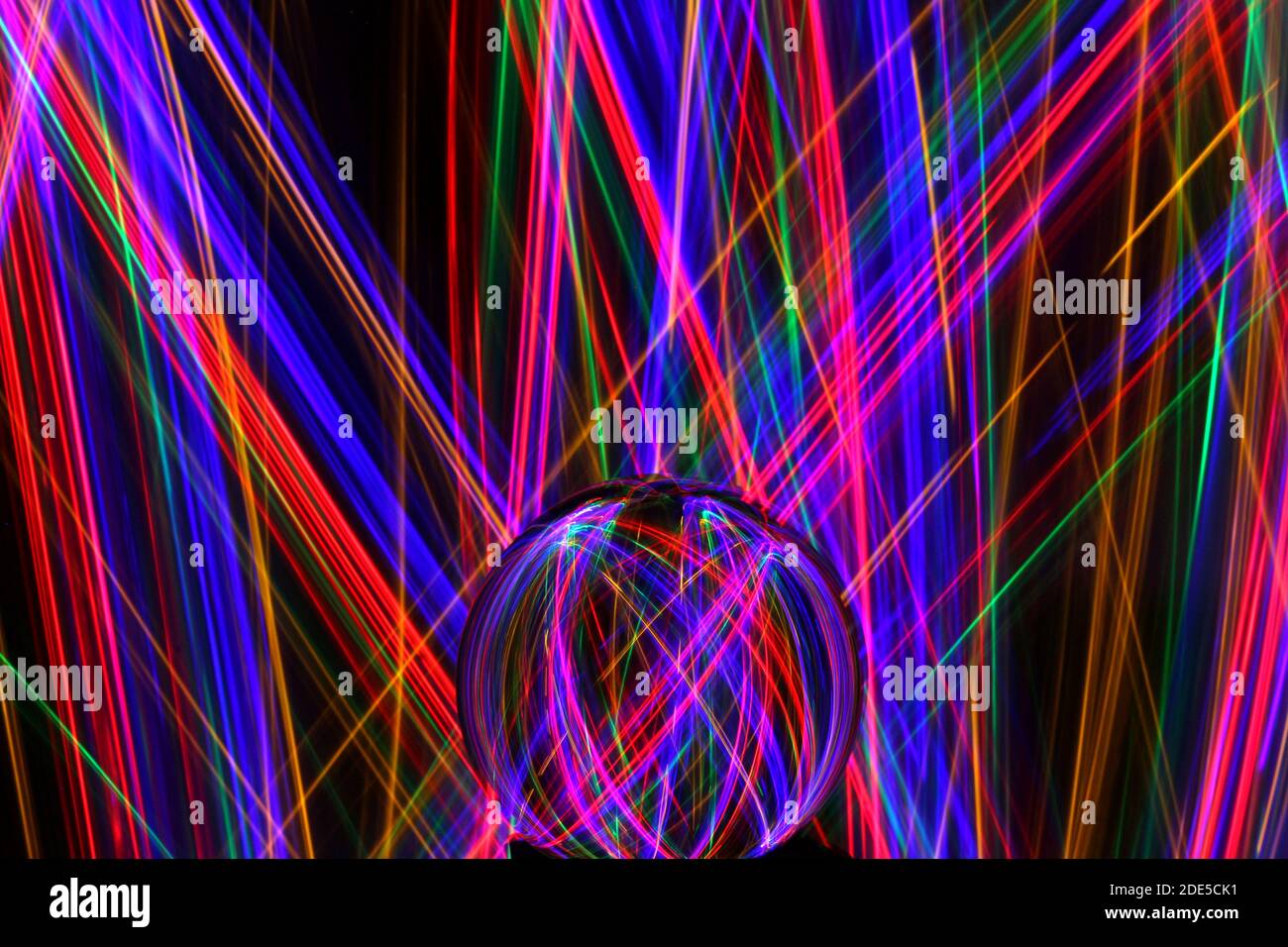 Fotografia a lunga esposizione di neon multicolore in un modello astratto di turbolenza con sfera di vetro riflettente. Fotografia di pittura leggera. Foto Stock