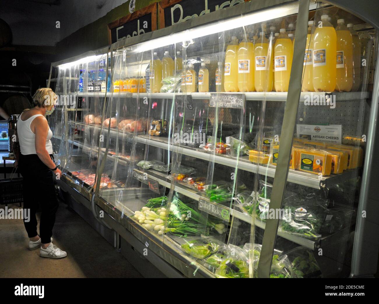 Una donna cliente perusa il cibo in esposizione al popolare mercato agricolo al coperto di Porterville. Foto Stock